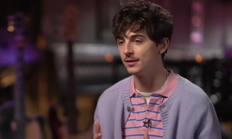 Timothée Chalamet, engaged in conversation with another person in front of the camera