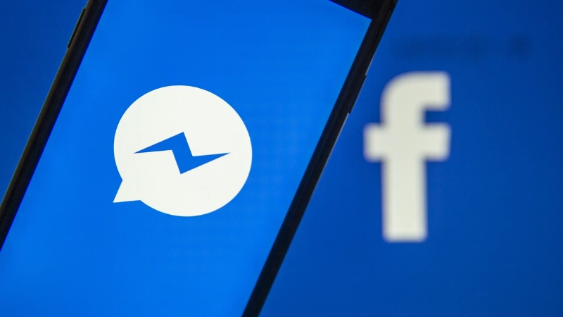 Phone screen showing the Messenger logo with a blurred Facebook logo in the background