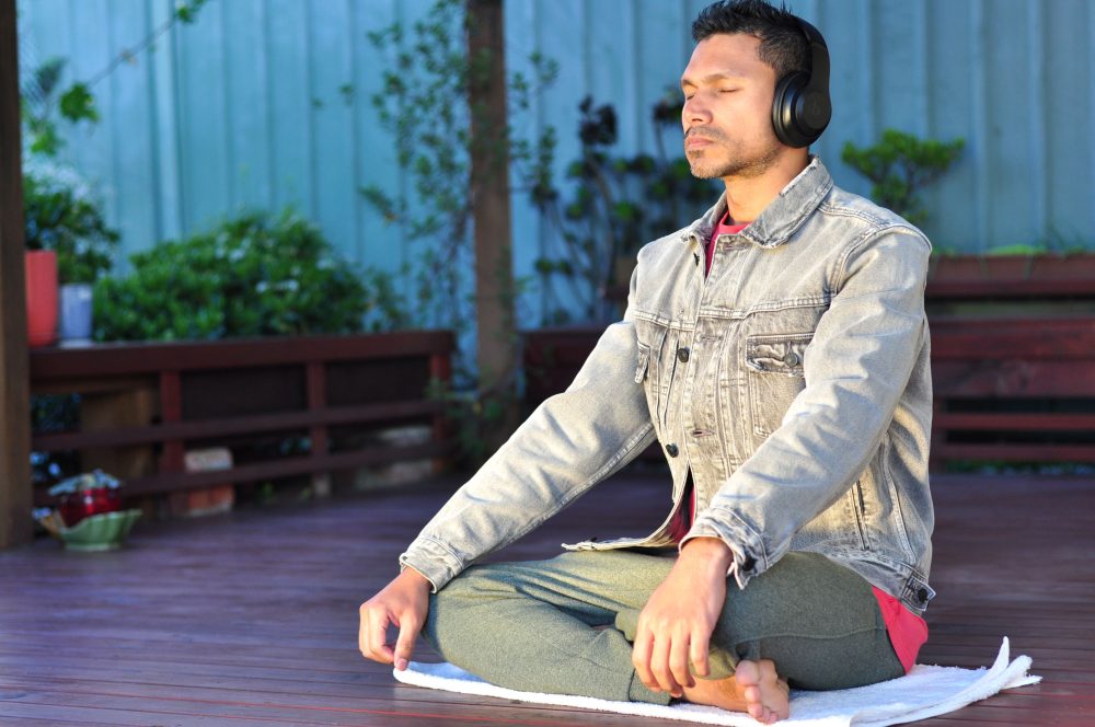 Man practicing guided meditation with headphones in a serene outdoor setting