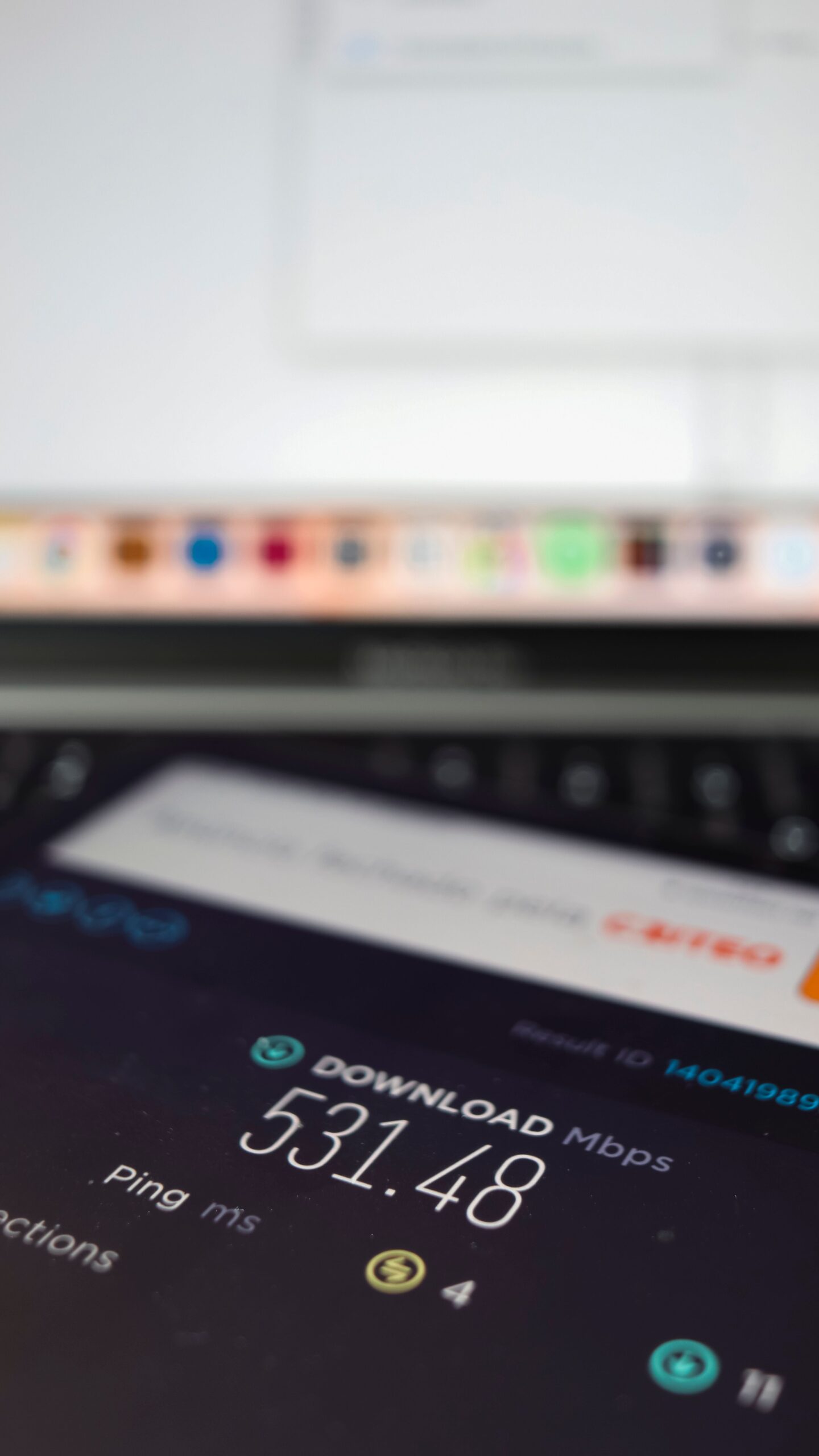 Close-up of a smartphone showing internet speed test results next to a laptop