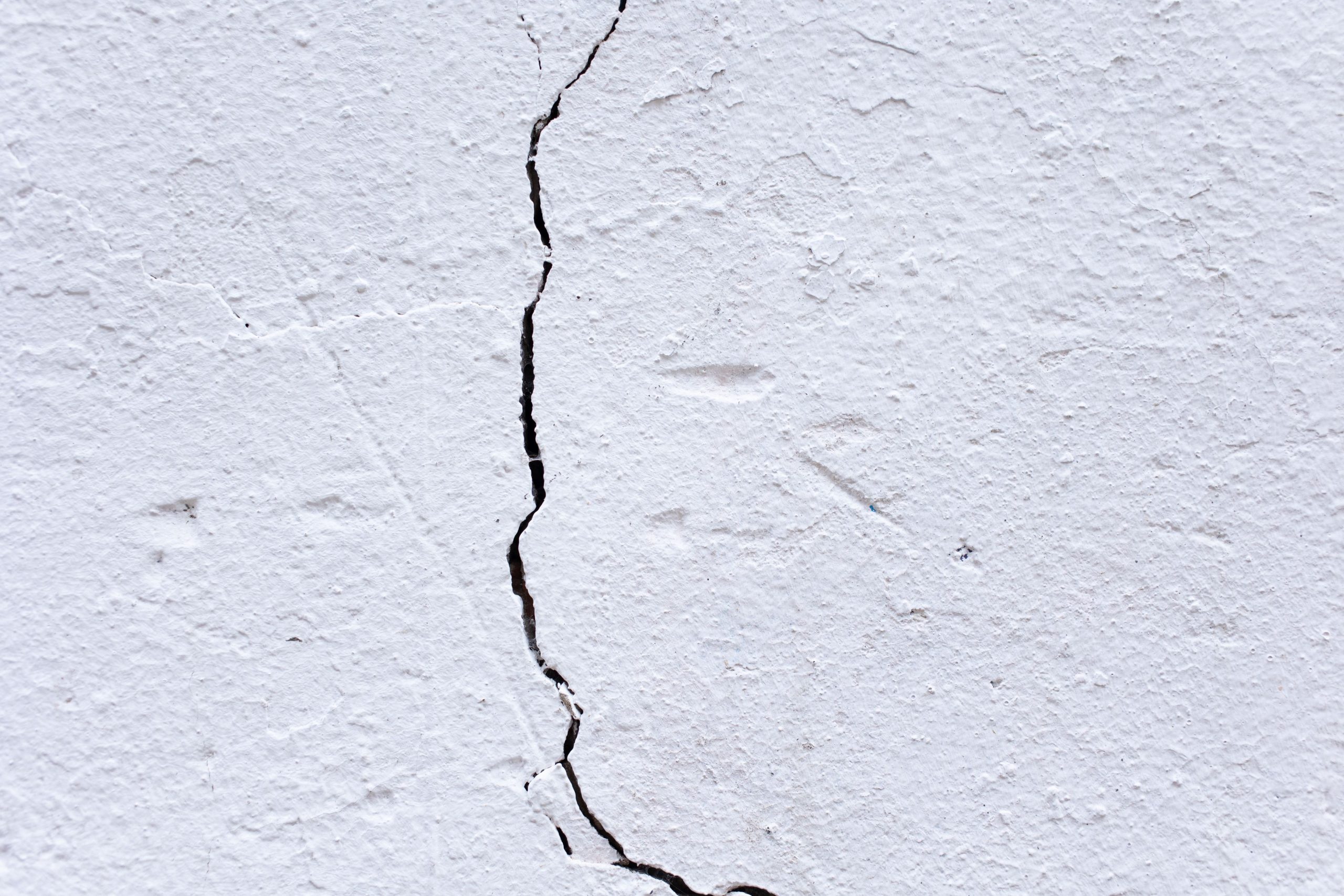 Cracked plaster wall with a large visible crack running through the surface