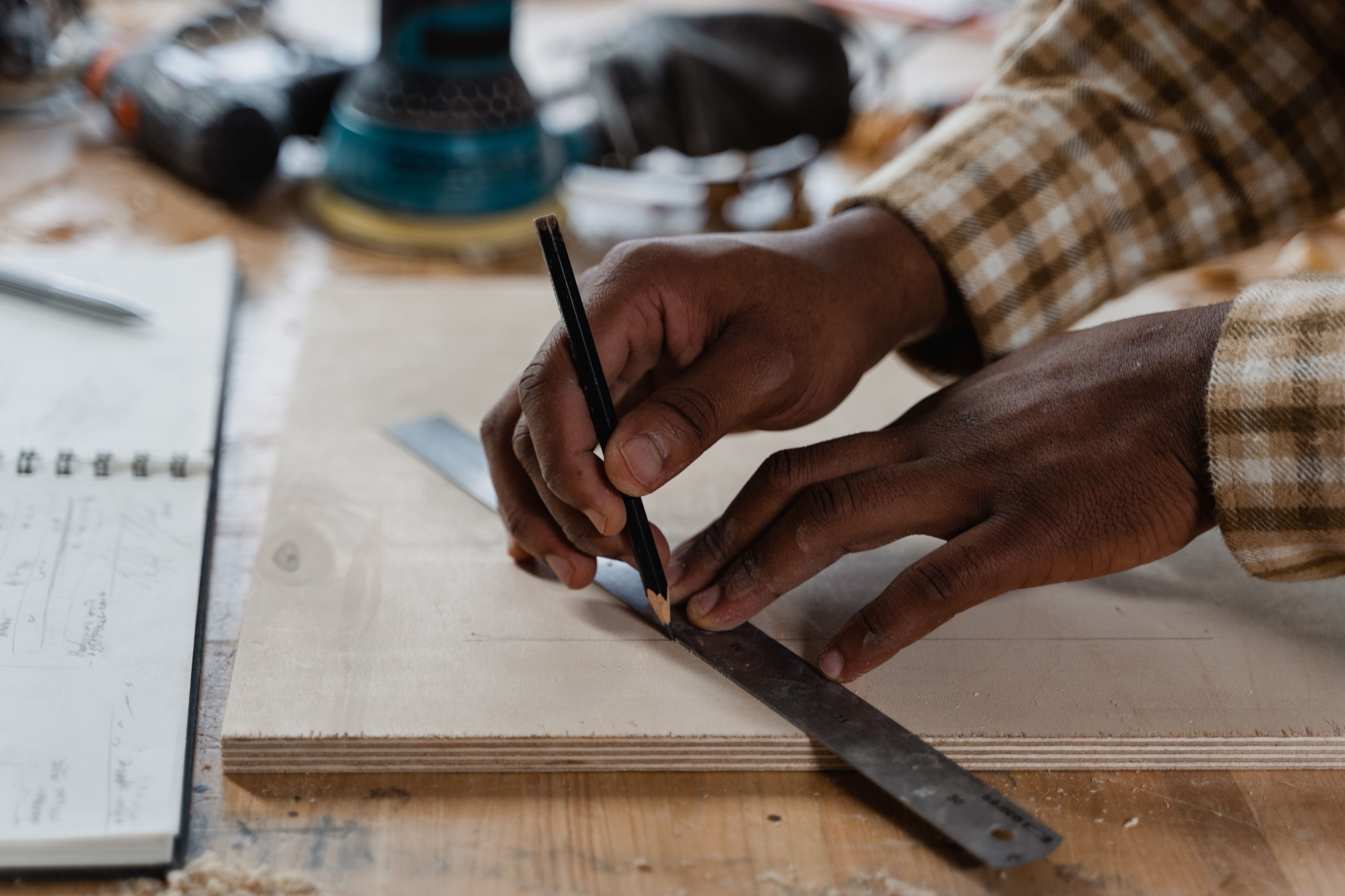 Craftsman measuring and marking wood while building a DIY display in a workshop