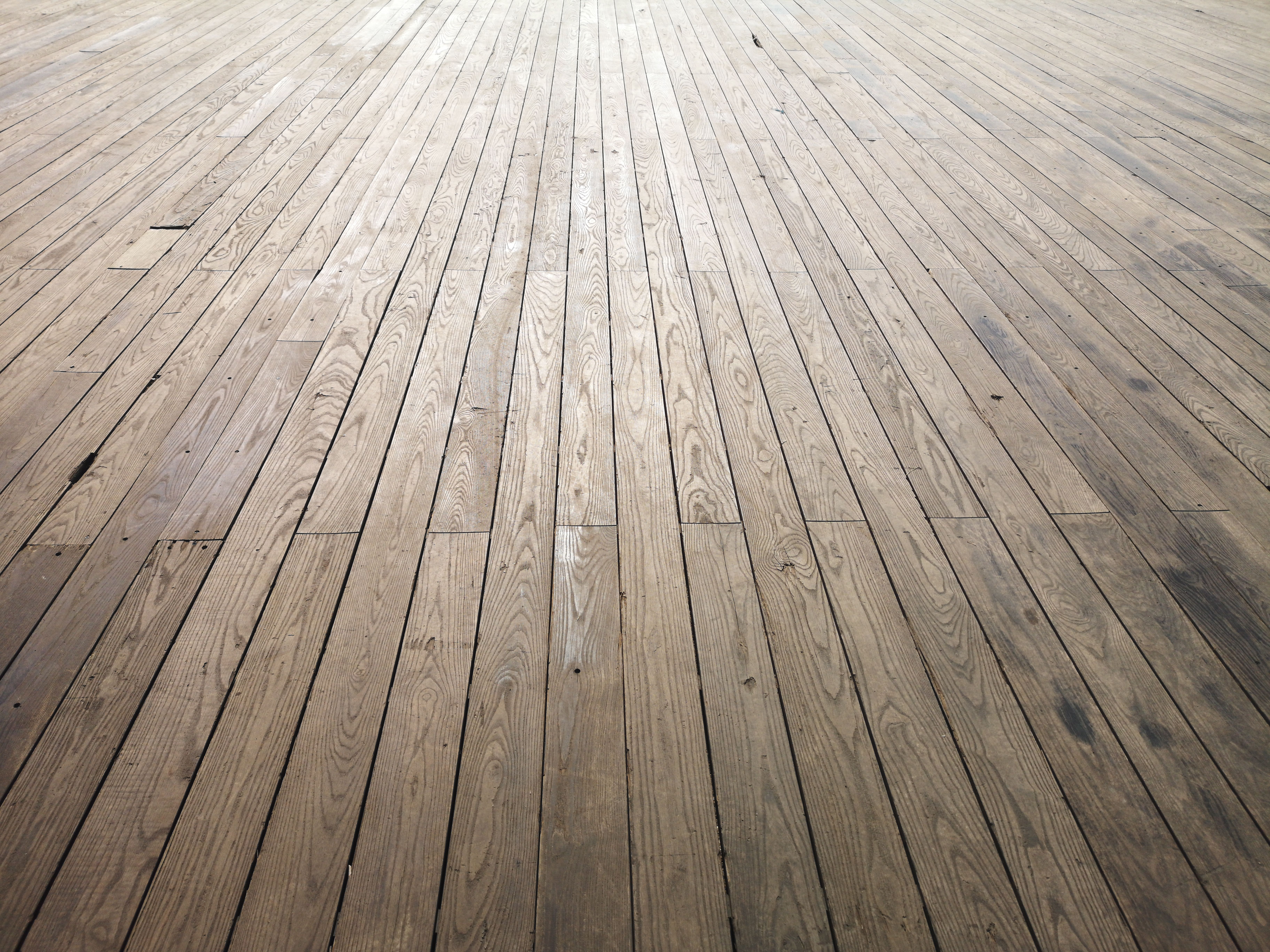 Wide angle view of dull aged wooden floor planks that look tired and in need of sanding and refinishing