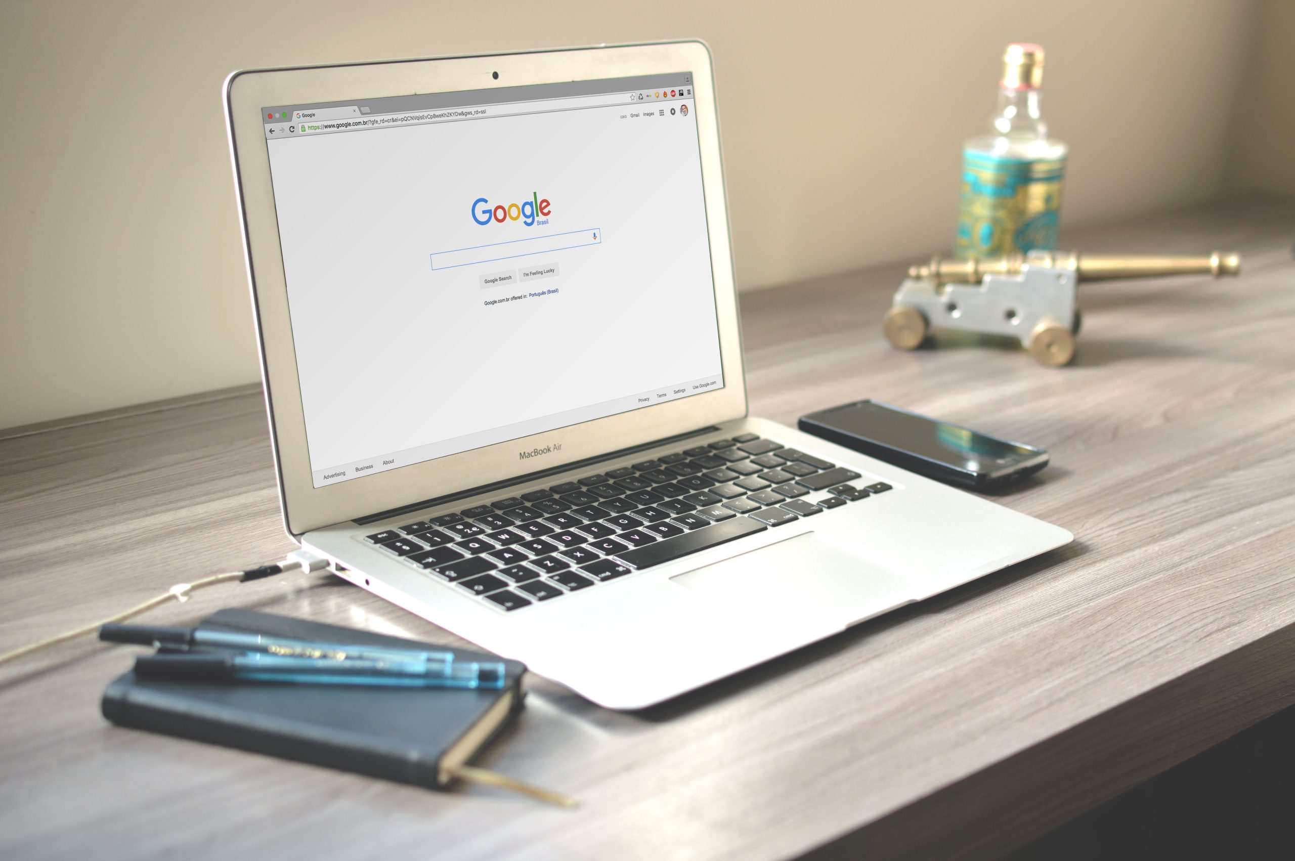 Laptop displaying a Google search results page on a tidy wooden desk with a notebook and smartphone