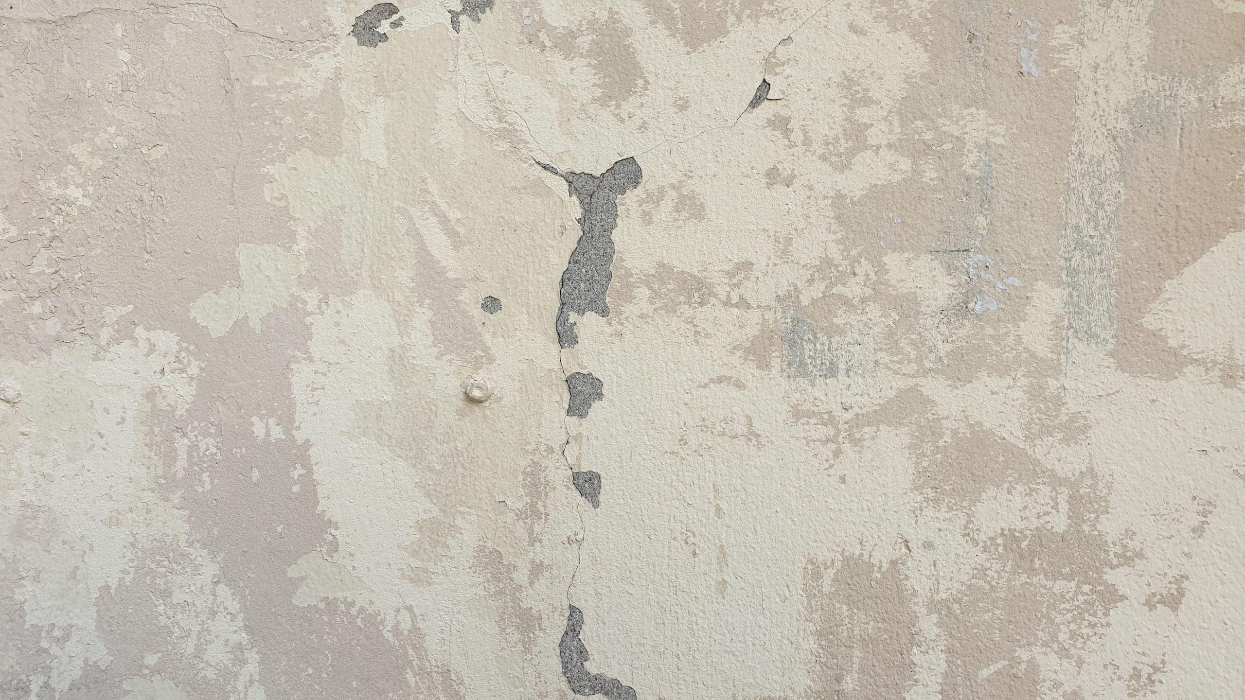 Close-up of a weathered home exterior wall with cracks and peeling paint
