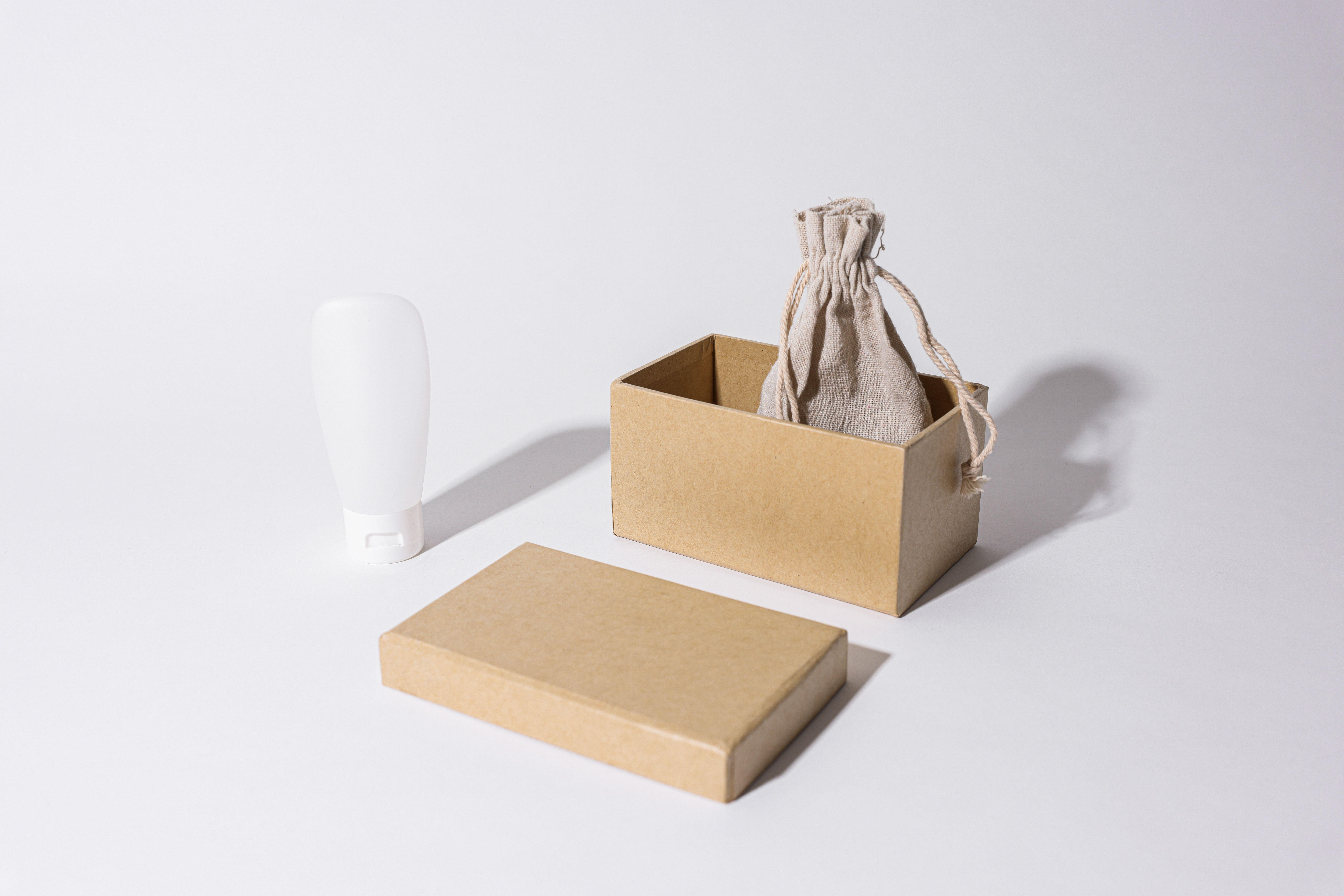 Minimalist product packaging mockup with cardboard box, linen pouch and cream tube