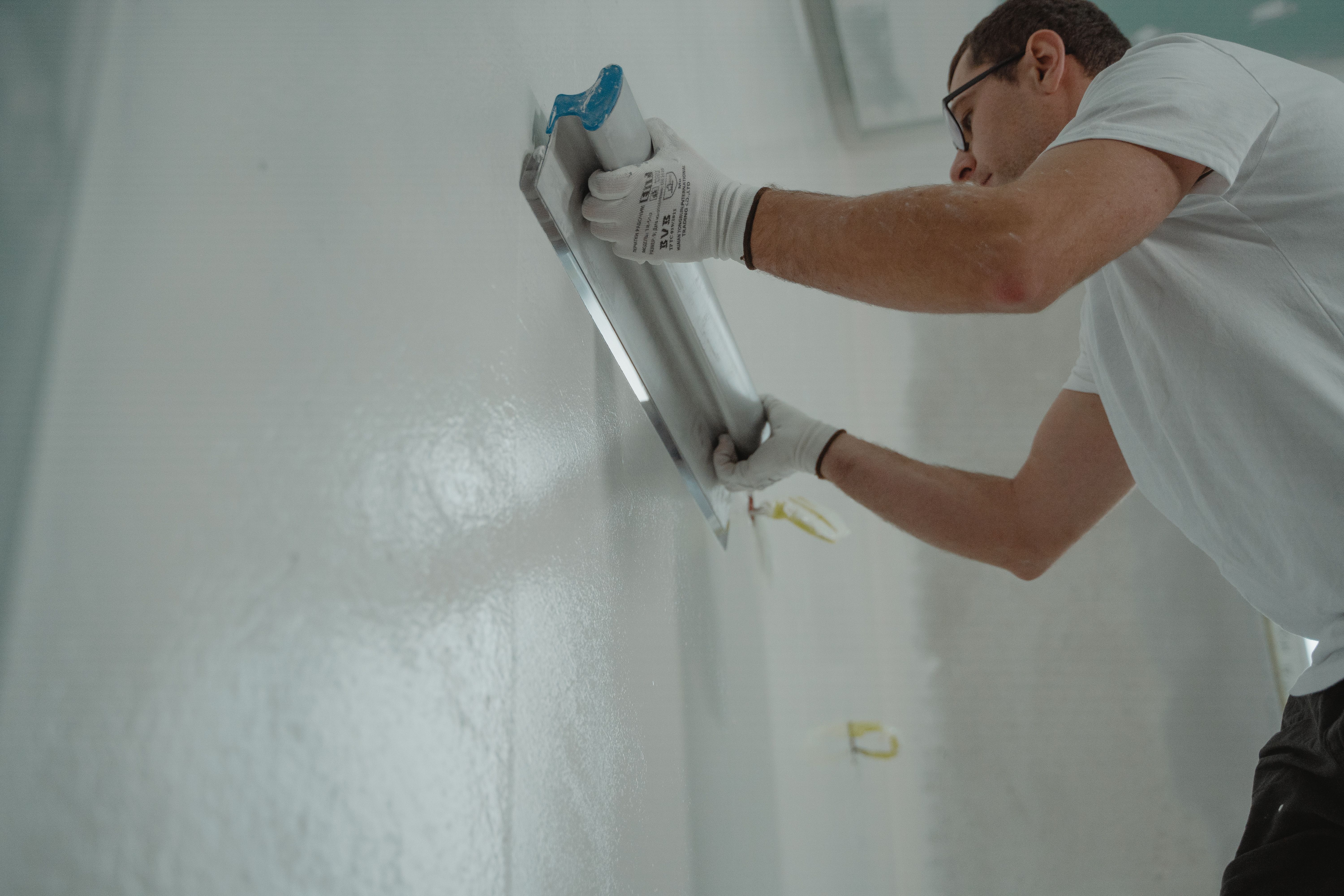Professional plasterer applying plaster to an interior wall for a smooth finish