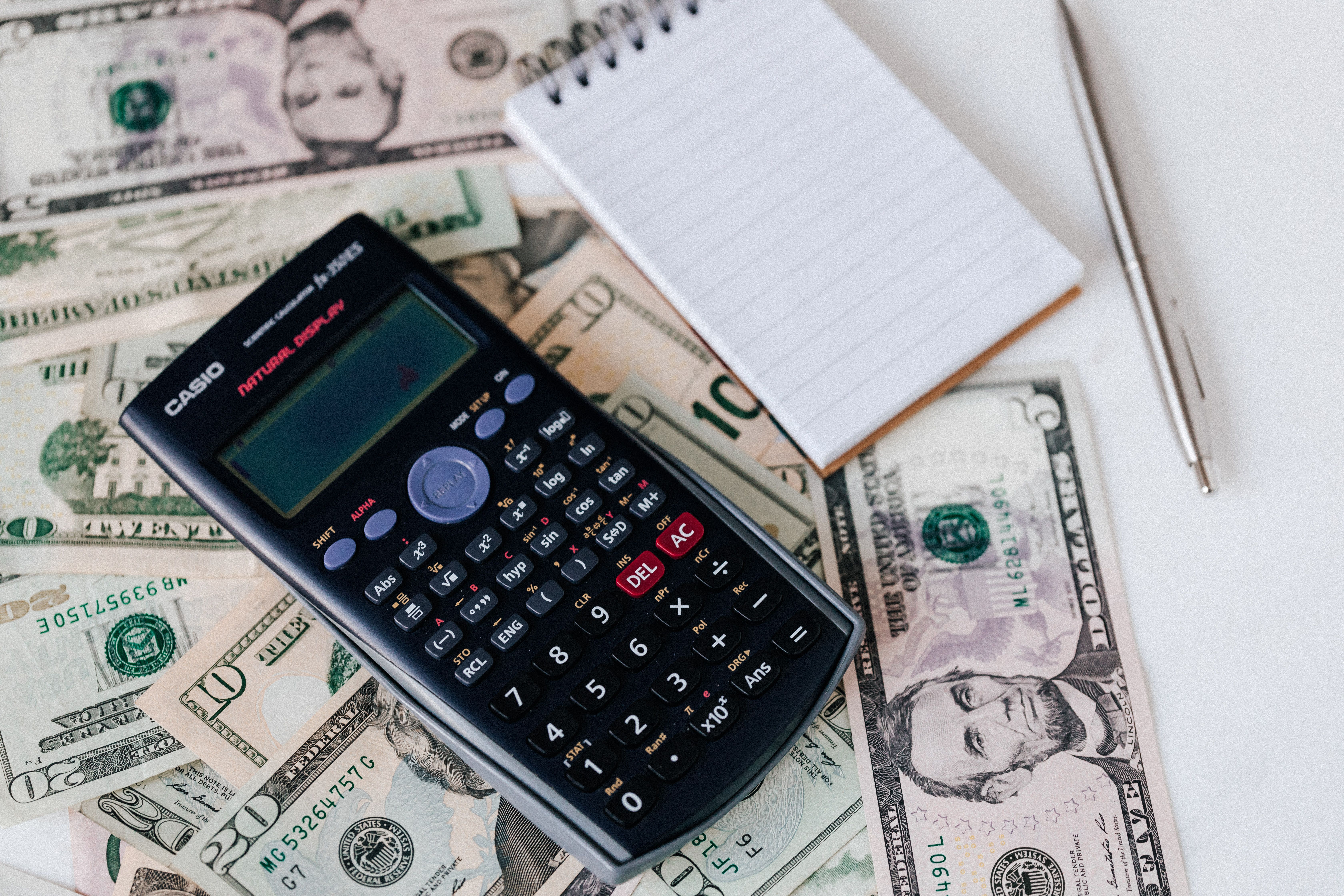 Calculator and notepad over dollar bills for budgeting a retail display investment