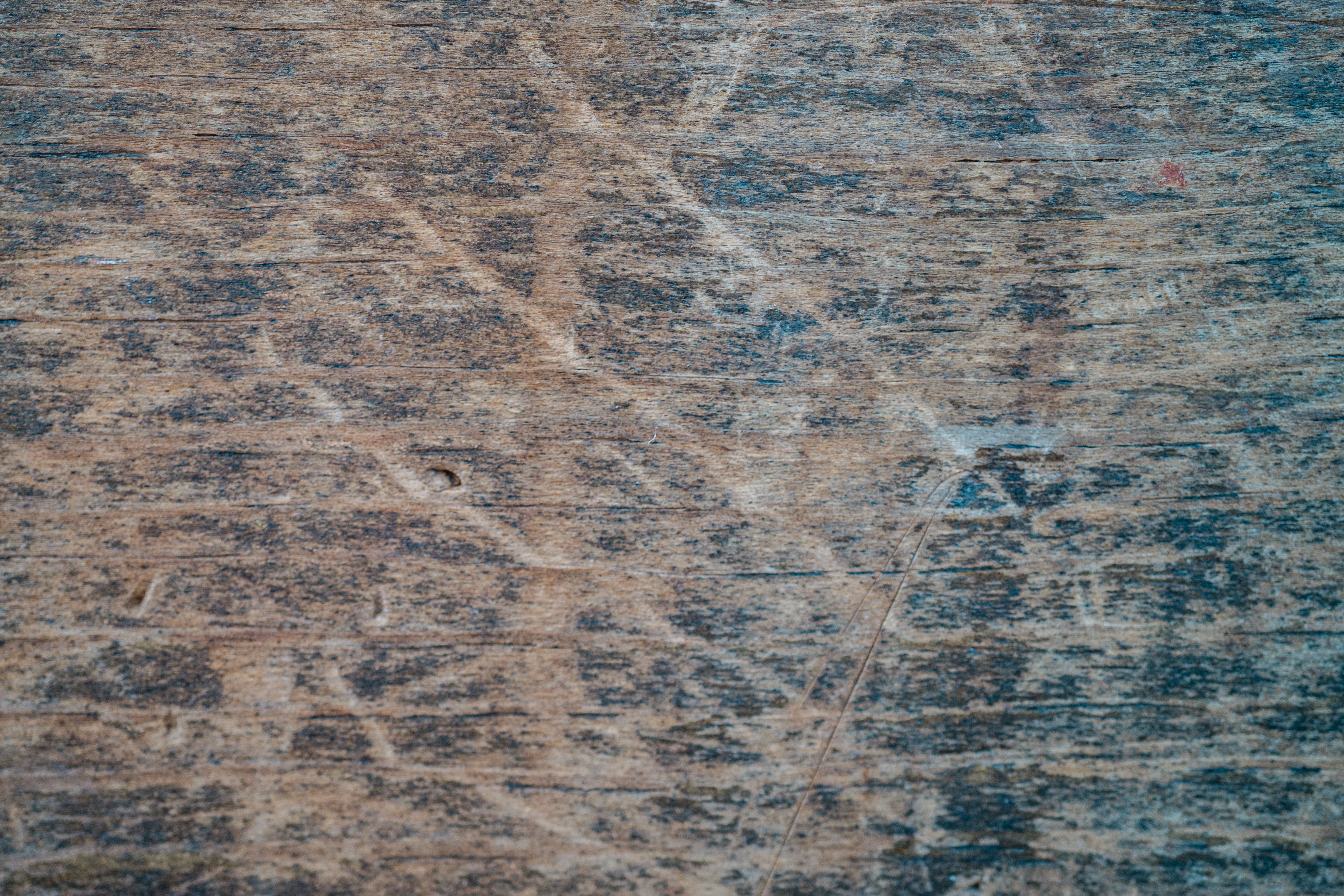 Close-up of a scratched and marked wood floor surface showing wear that requires sanding