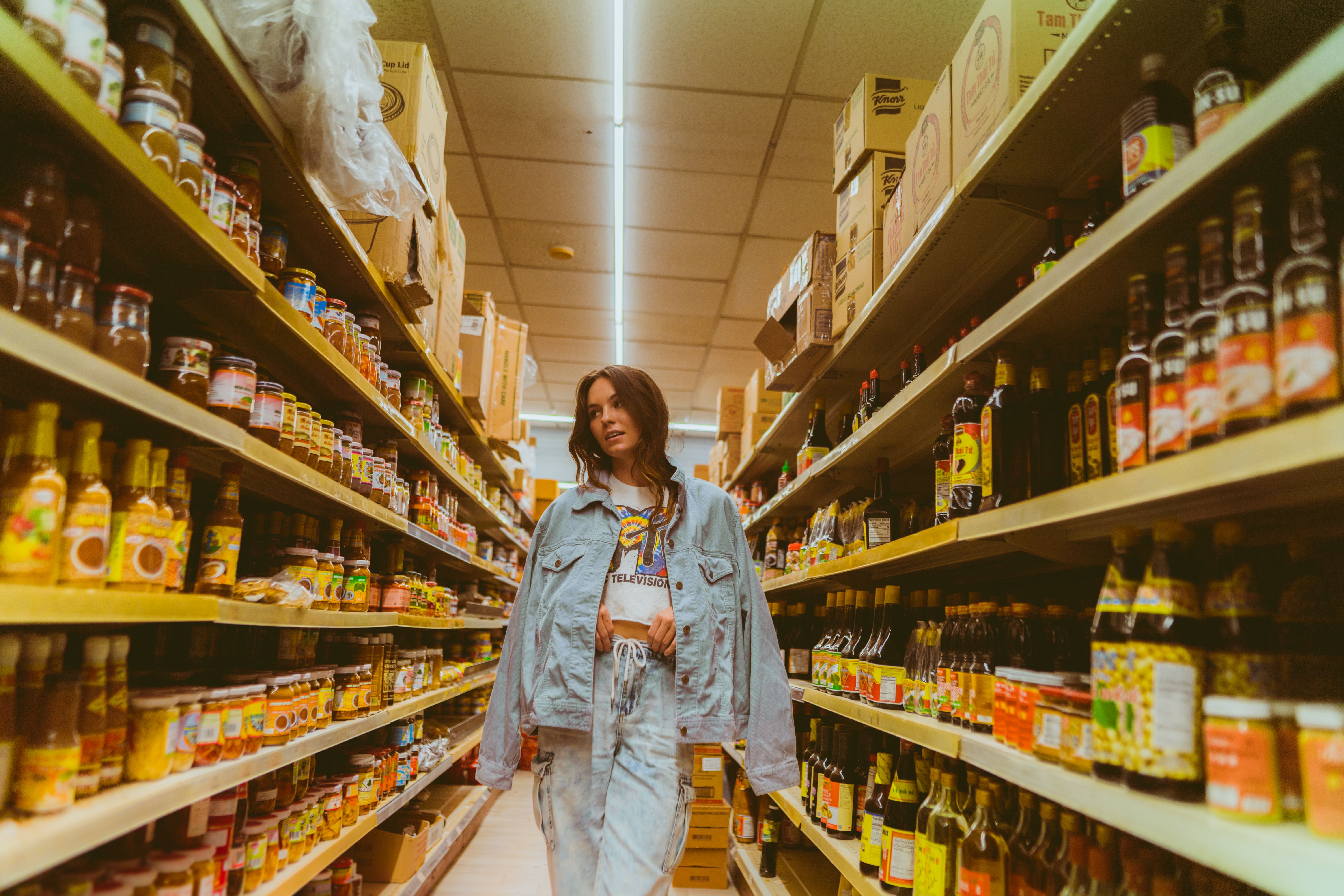 Woman browsing products in a grocery store aisle, a shopper making unplanned purchase decisions