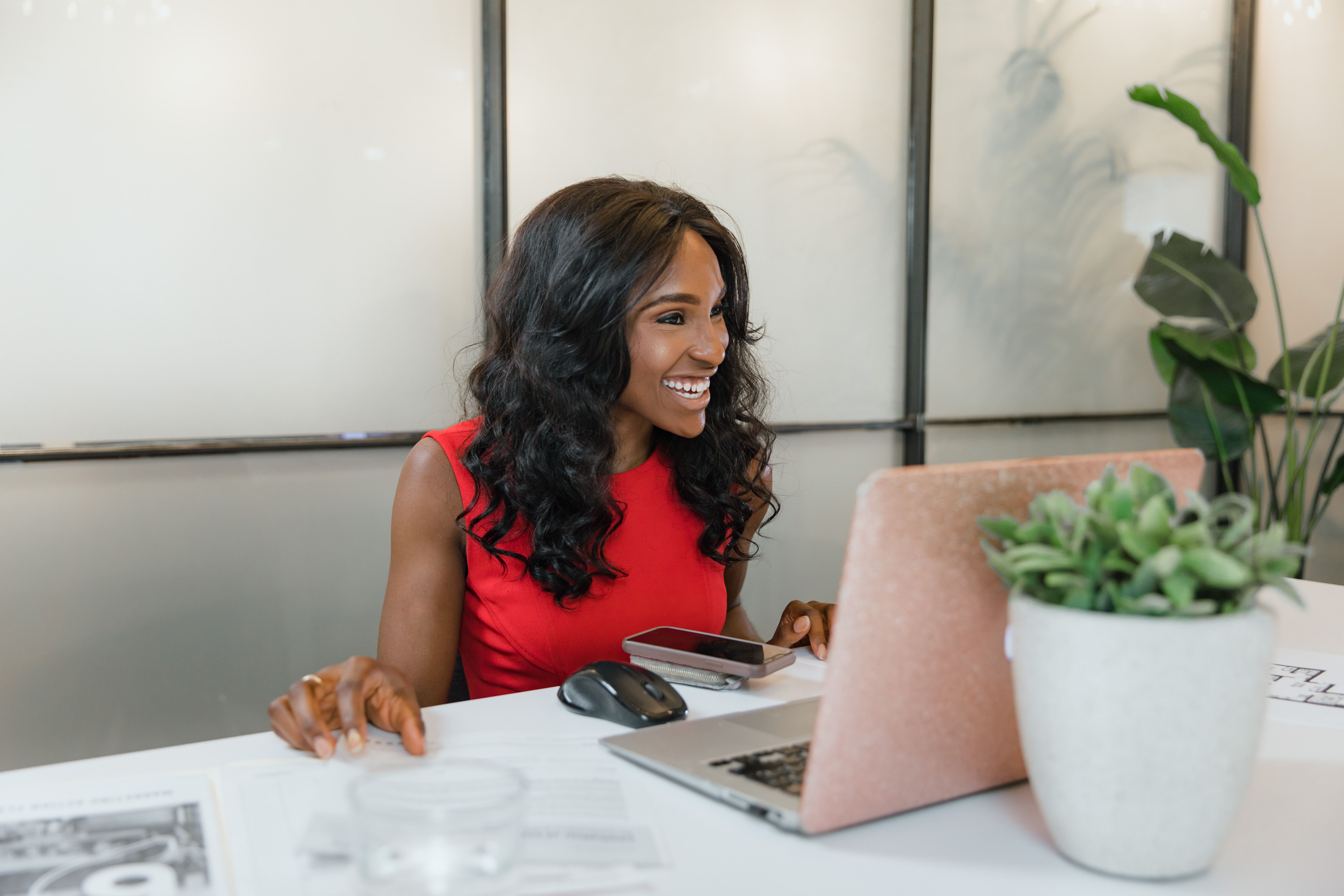Small business owner working on her laptop and smartphone at an office desk