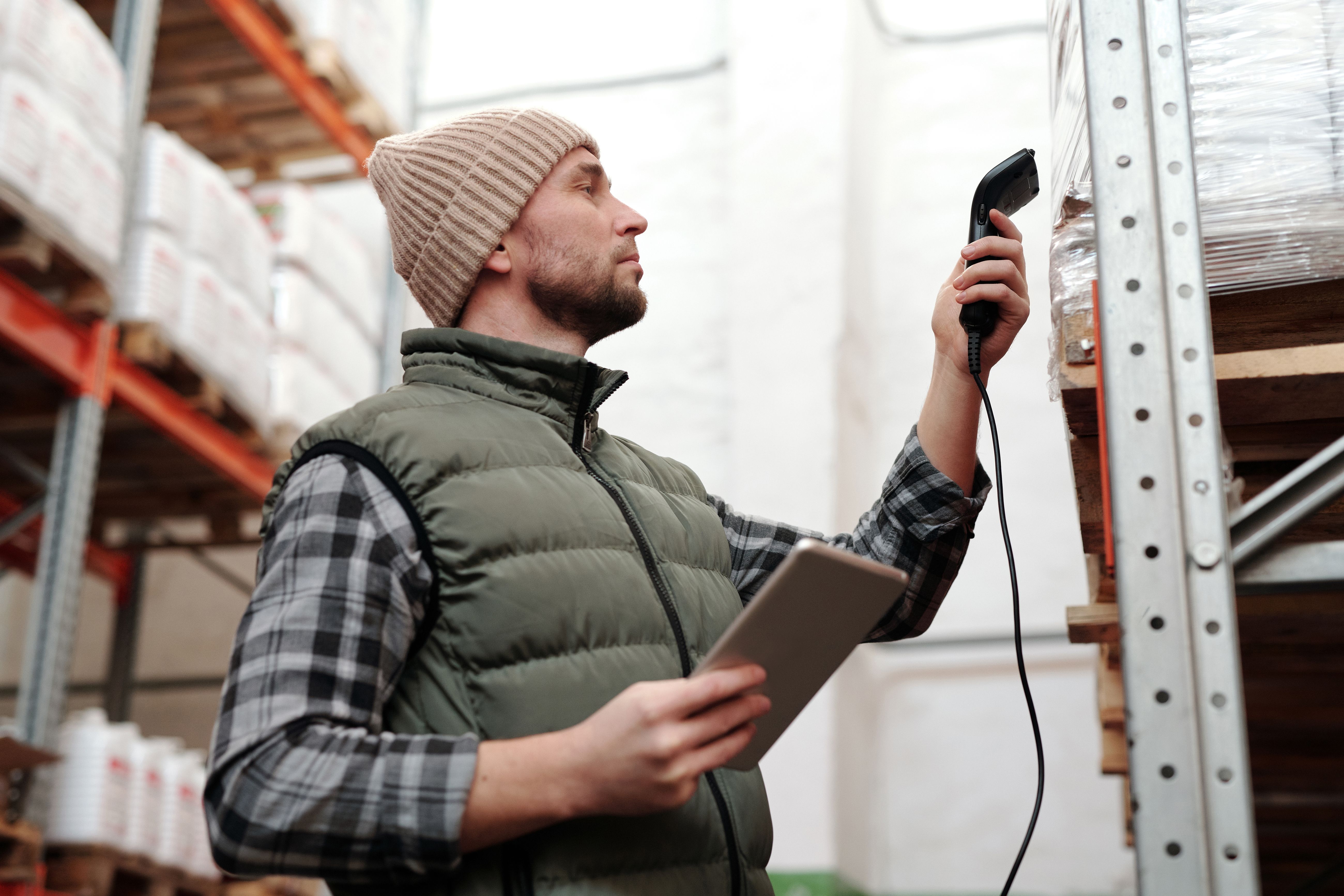 Warehouse worker scanning inventory with a handheld scanner and tablet for order fulfillment