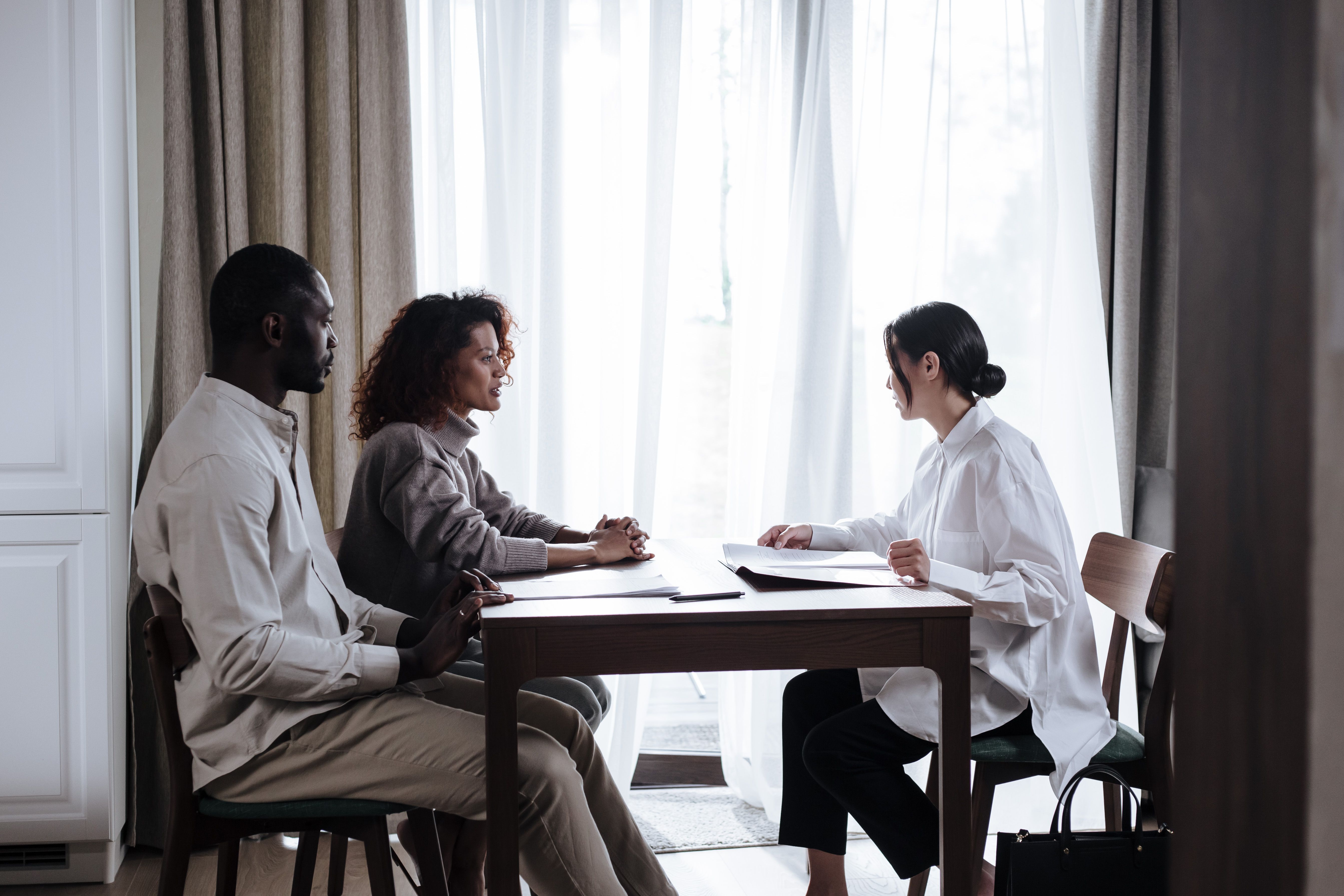 Couple and advisor reviewing documents together at a table, representing a wedding planning consultation