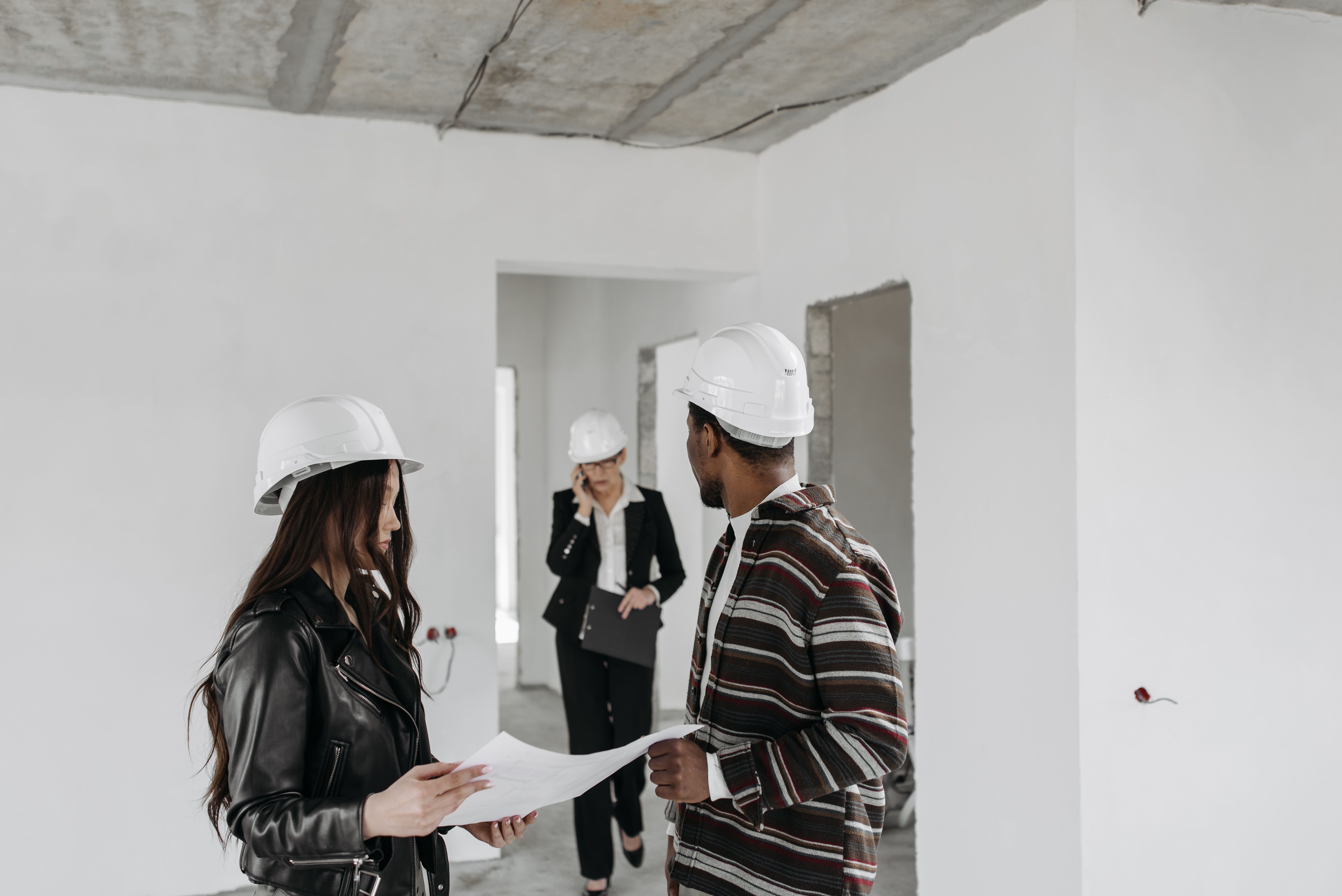 Diverse construction team in hard hats reviewing blueprints inside a building project