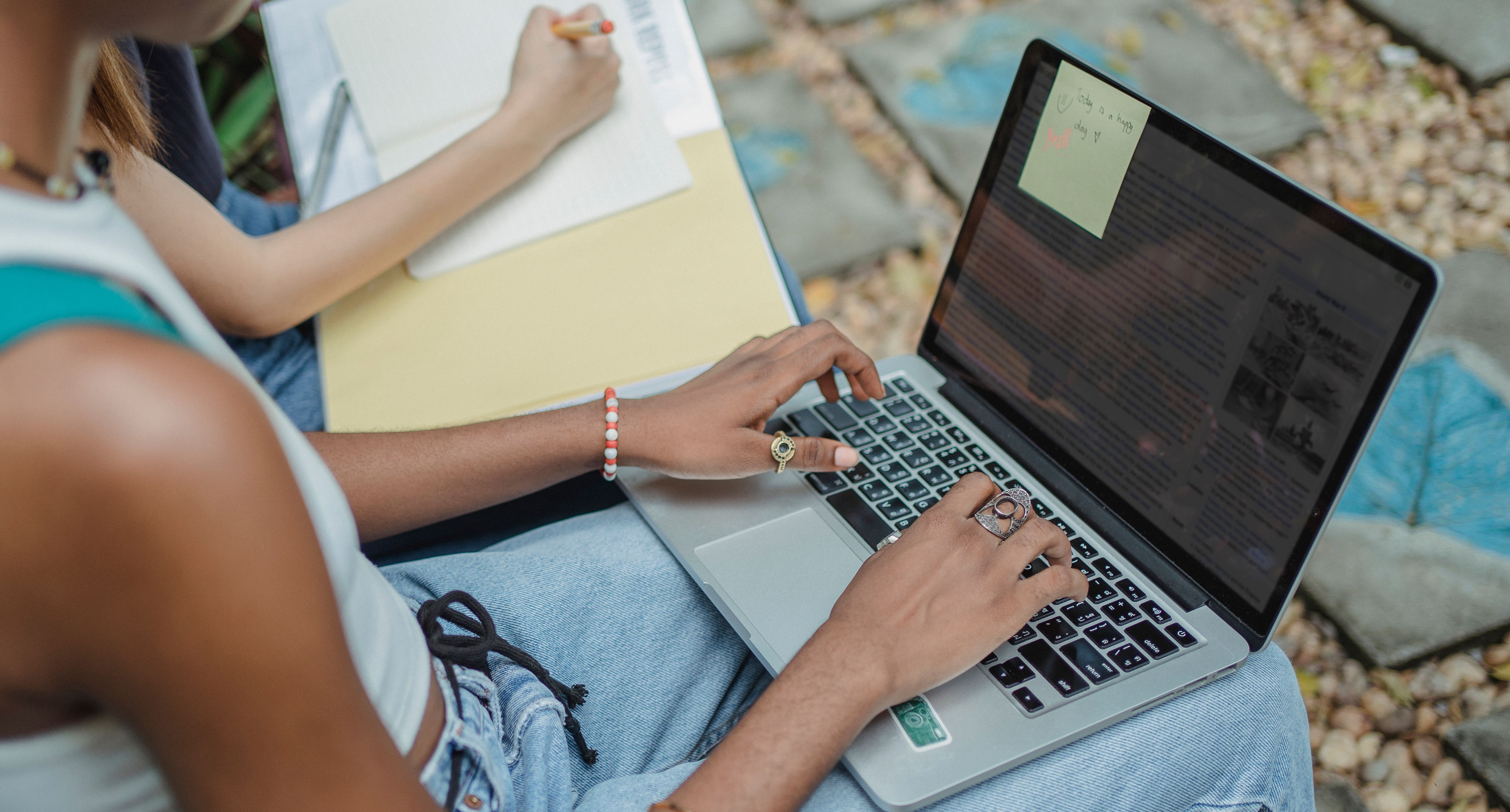 Students using a laptop and writing notes together while working on an assignment