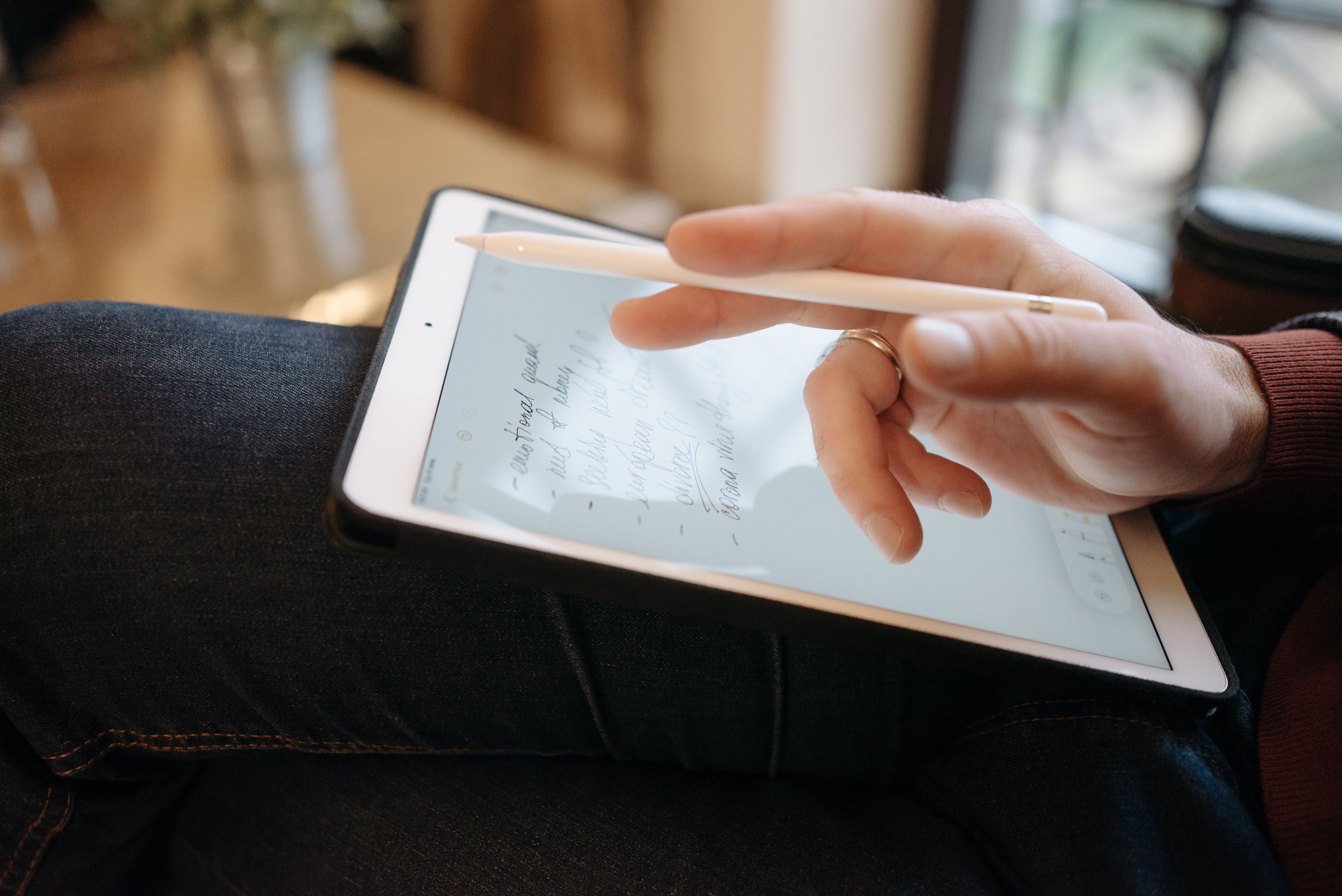 Close-up of a hand writing notes on a tablet with a stylus