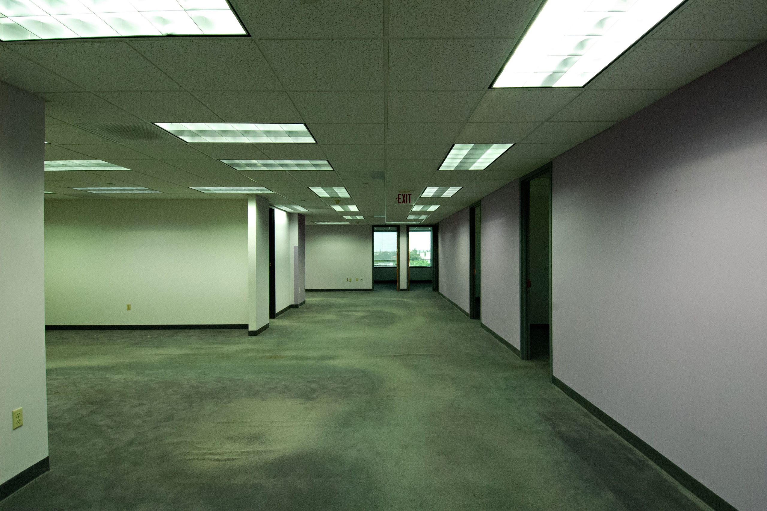 Spacious empty office with fluorescent lights, ready for leasing or renovation