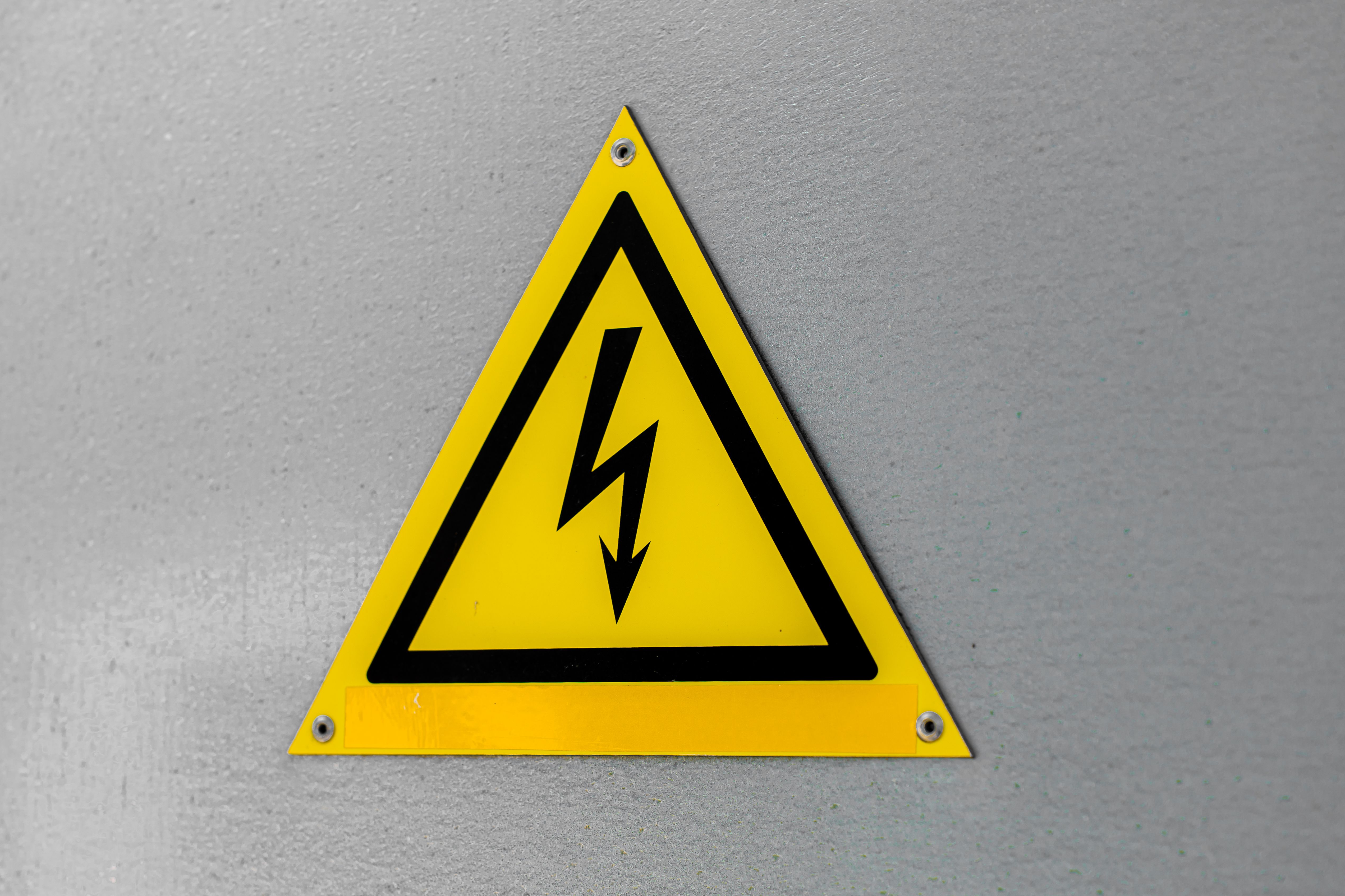 Close-up of a yellow high voltage warning sign mounted on a wall