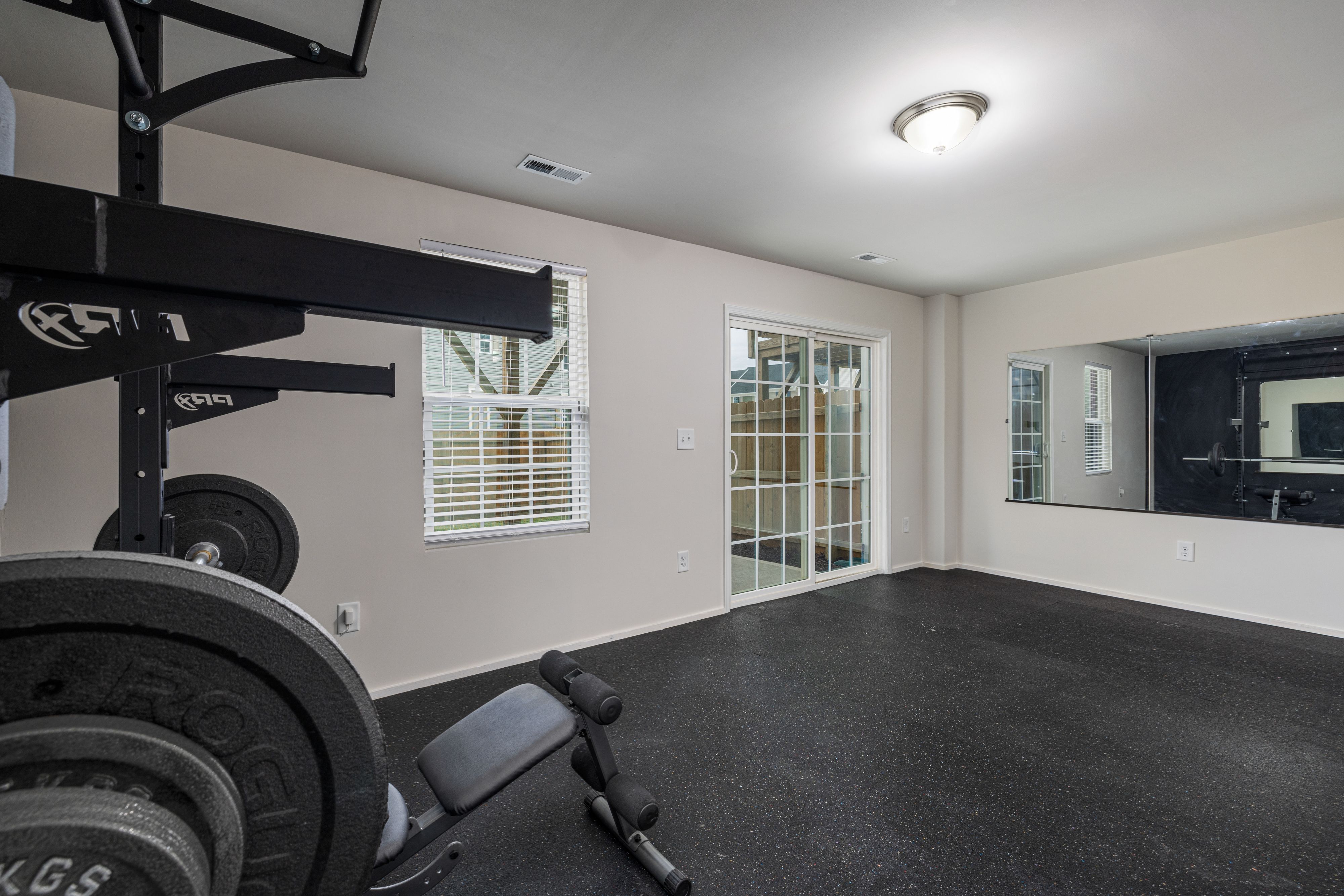 Well-lit home gym with modern weightlifting equipment and a large mirror