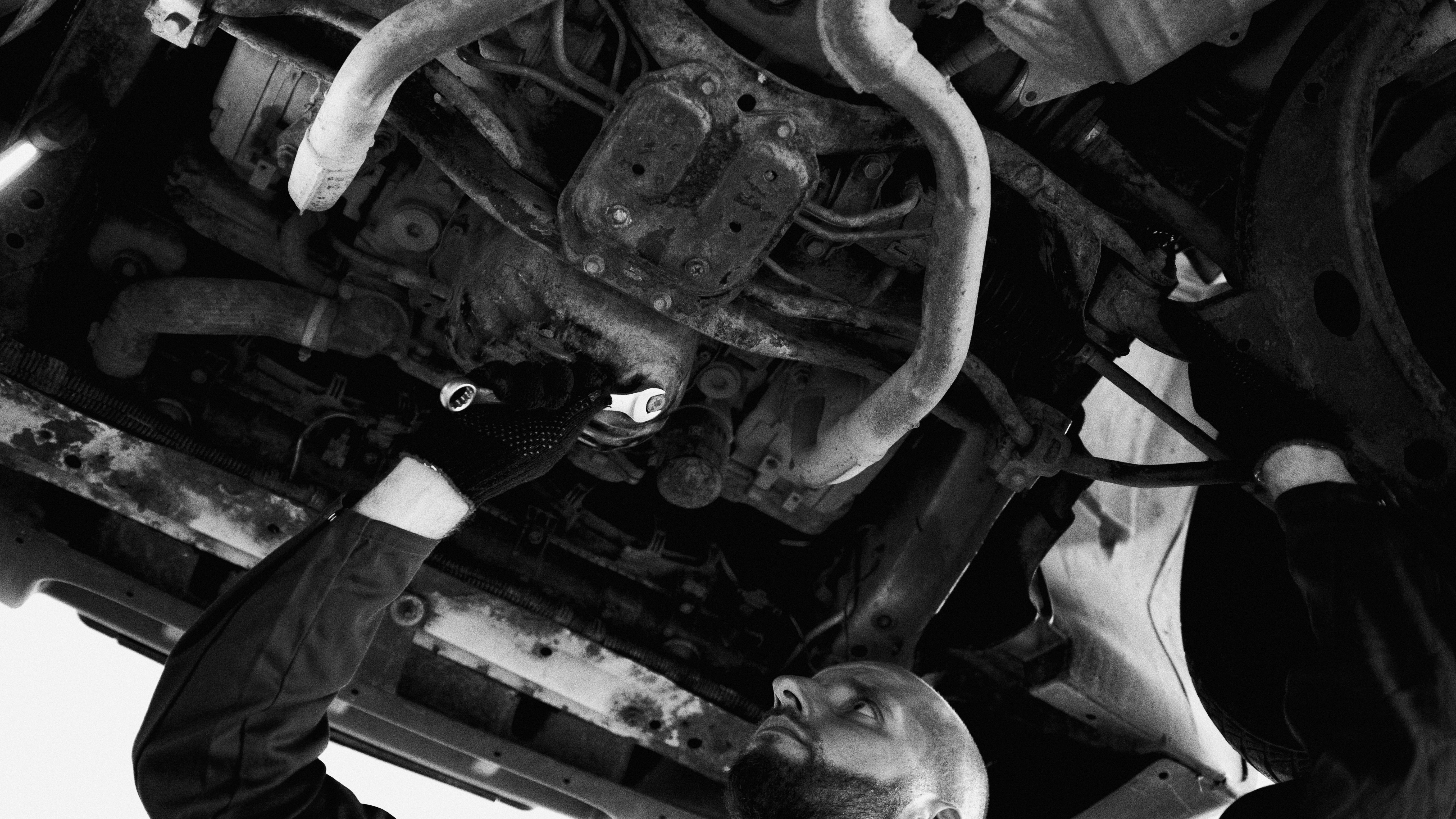 Mechanic inspecting a vehicle's undercarriage in a workshop, illustrating a pre-purchase inspection.
