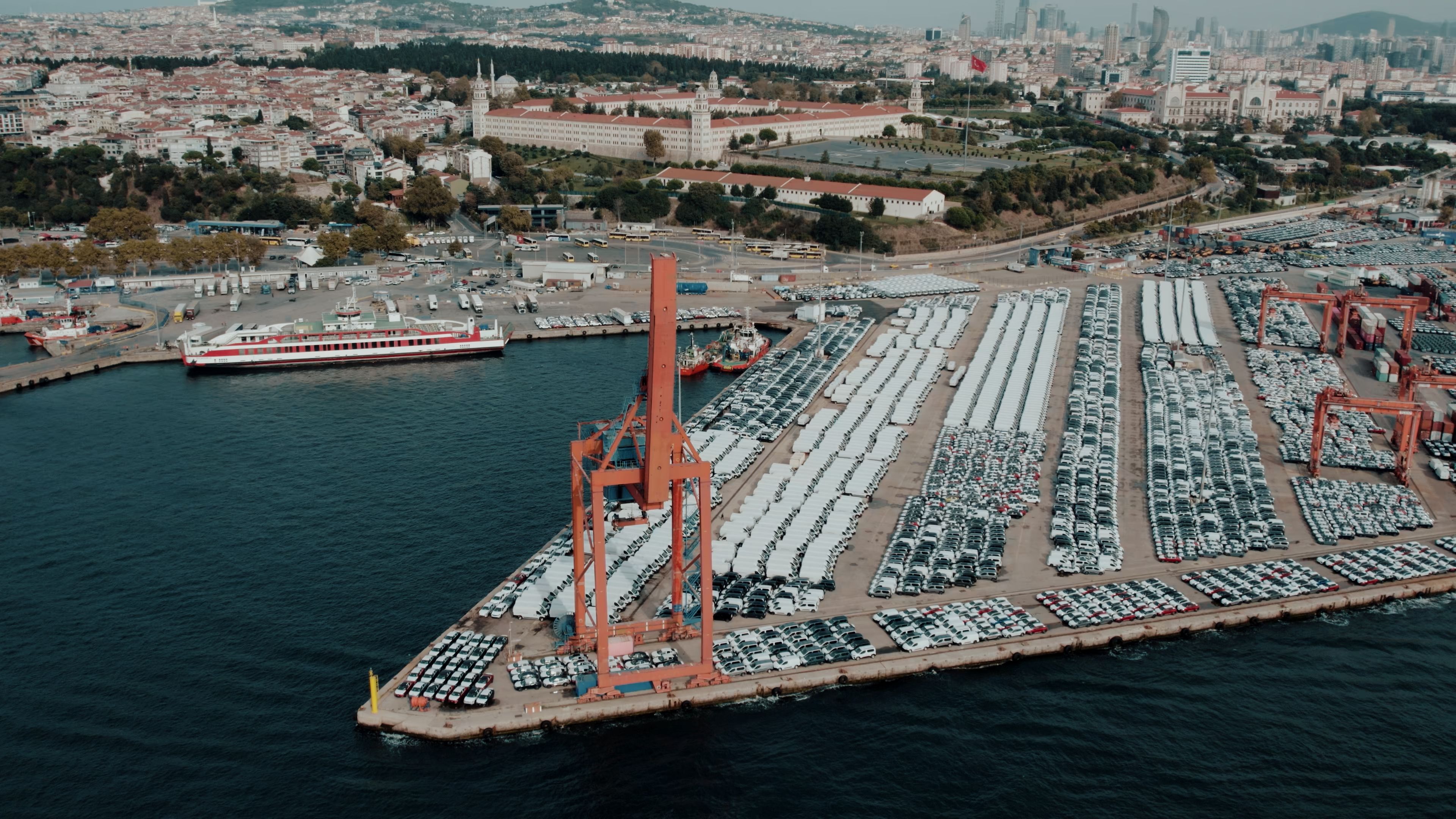 Aerial view of vehicles waiting at a busy port terminal, representing international car shipping.