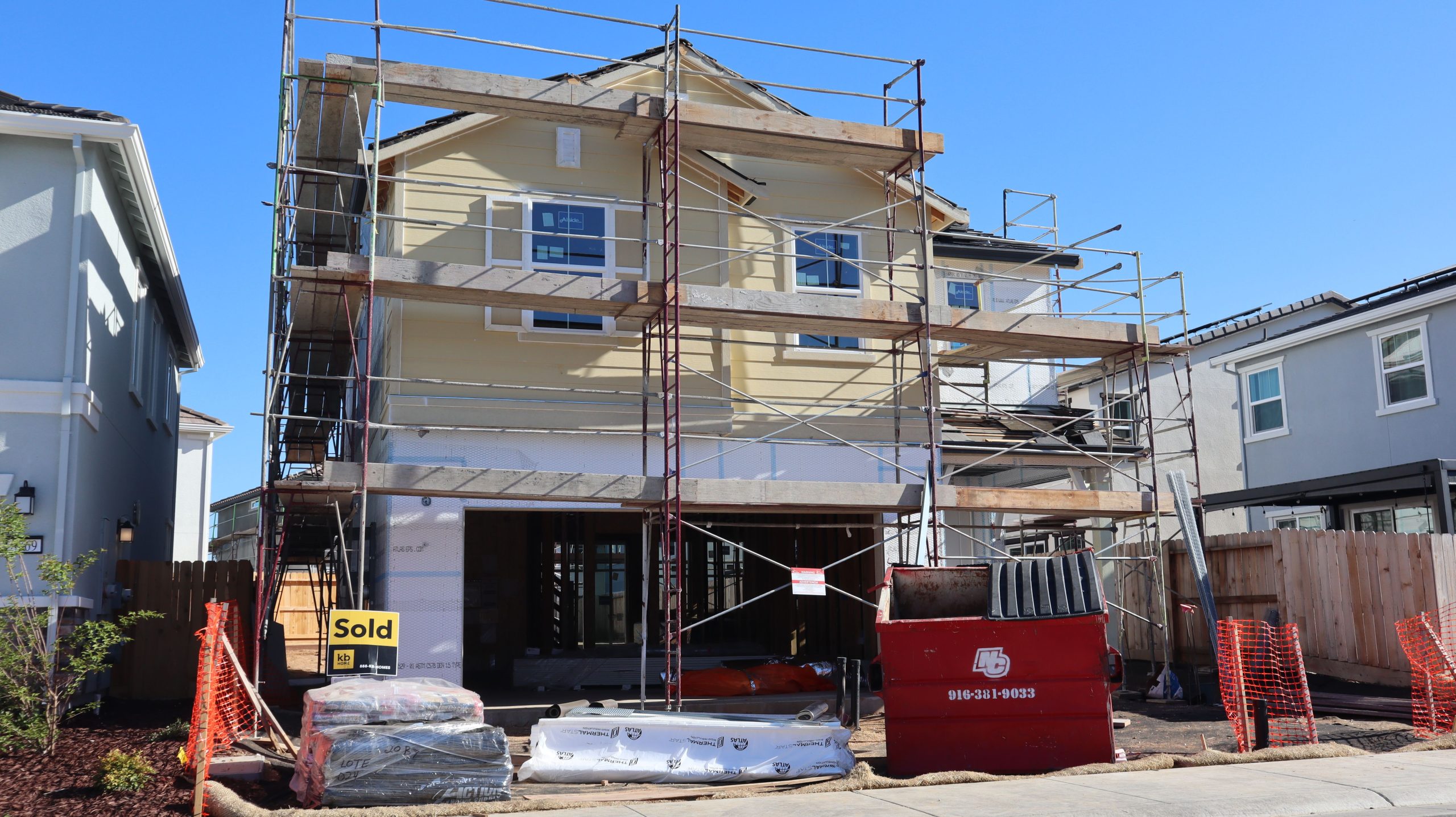 Under-construction house with scaffolding and a sold sign out front