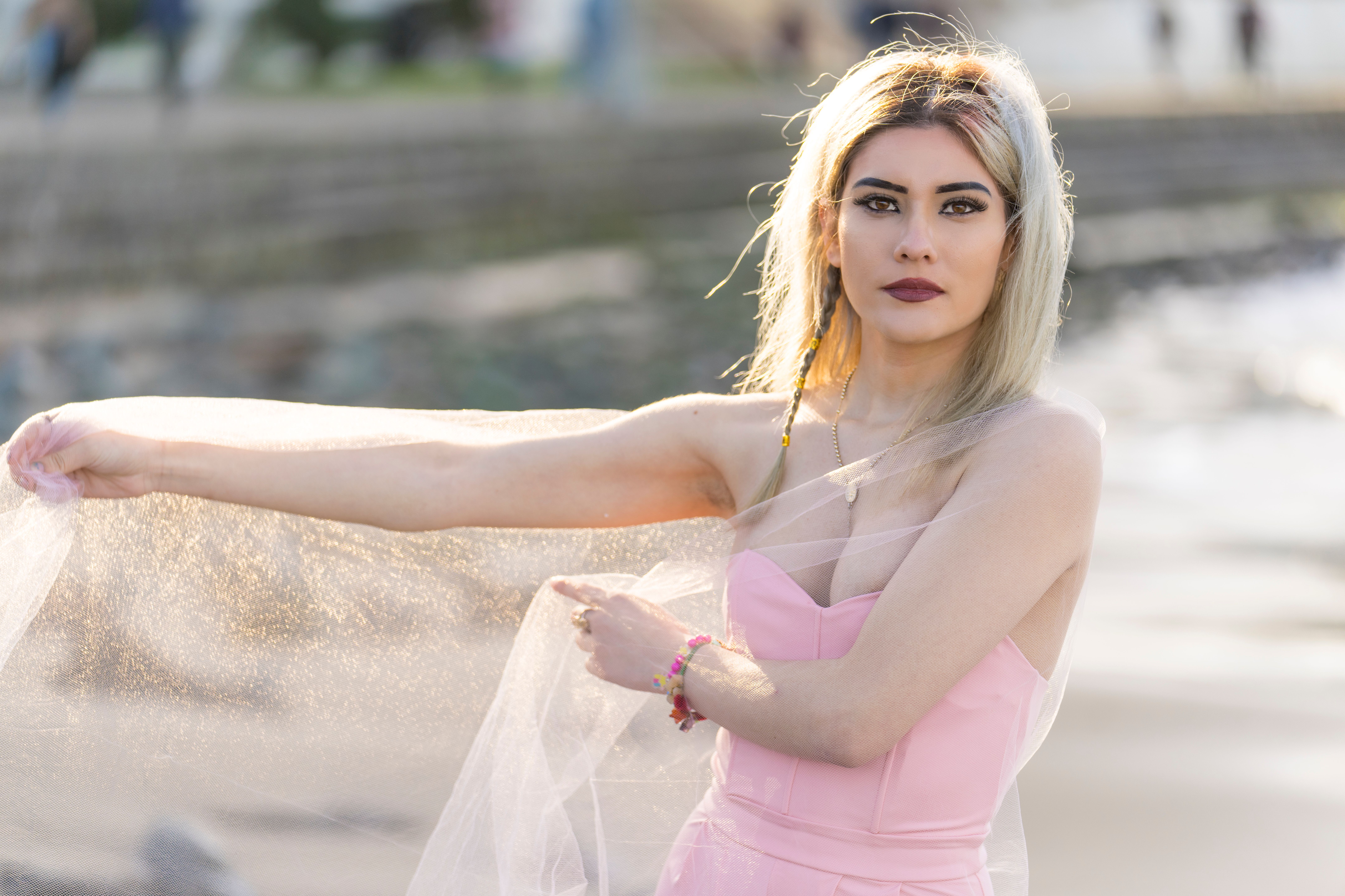 Woman confidently wearing a strapless pink dress at the beach, no visible bra straps