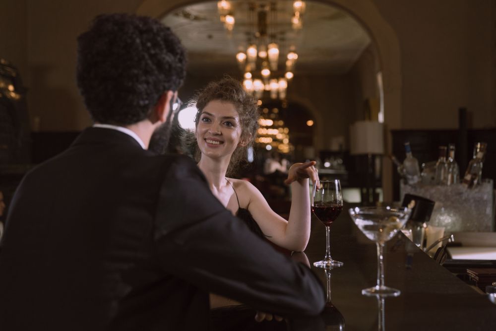 Well-dressed couple sharing wine at an upscale bar during an intimate evening out.