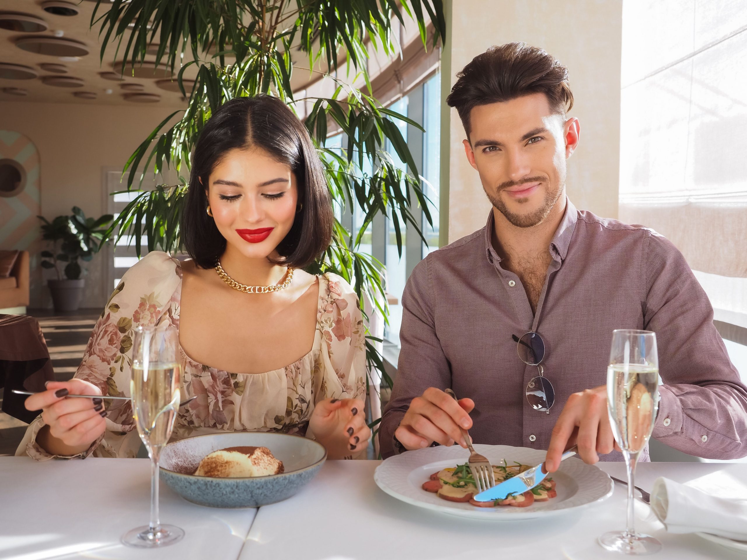 Stylish couple sharing a gourmet dinner and champagne at an upscale restaurant, illustrating the luxury dating experience.