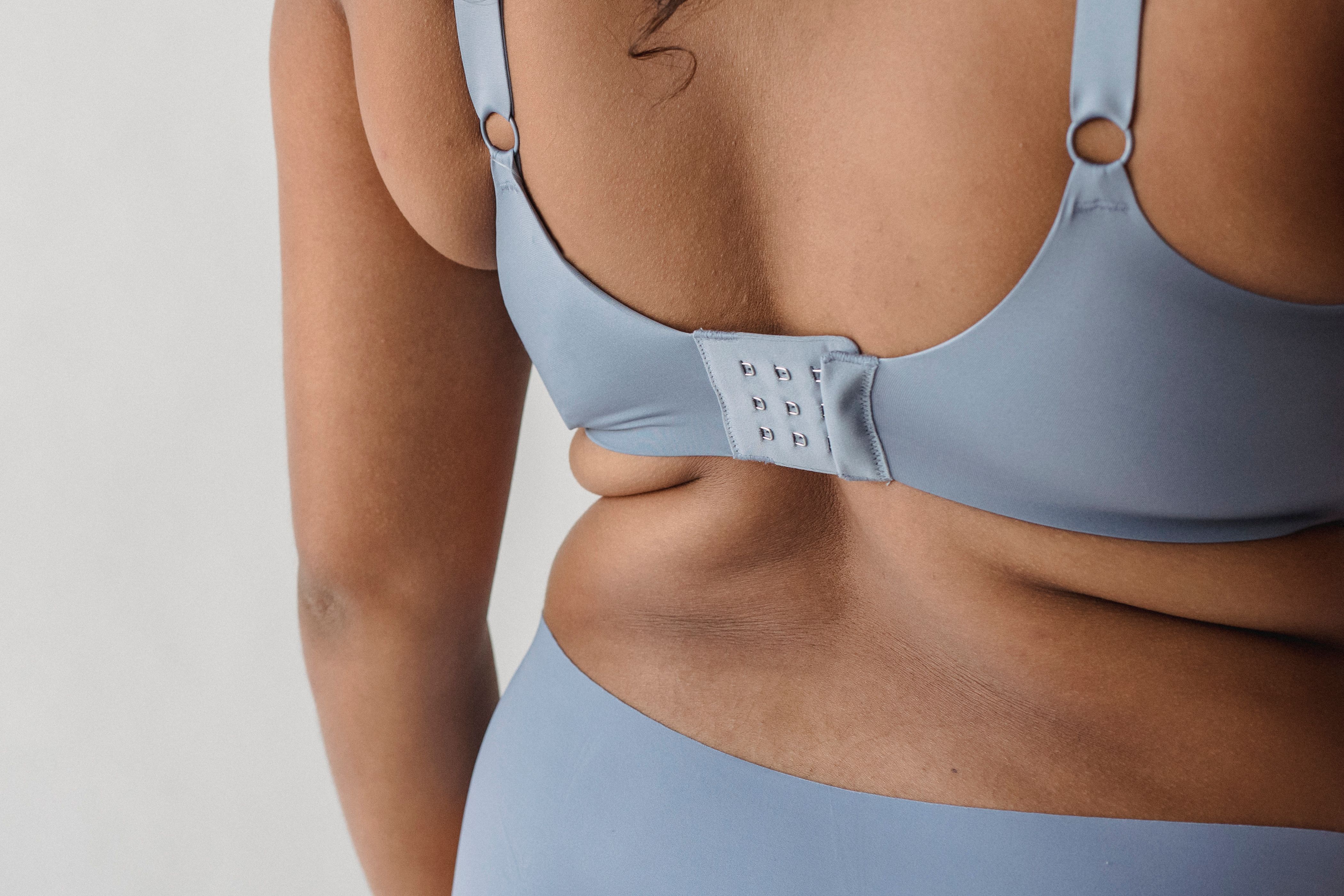Close-up of traditional bra clasp on woman's back, illustrating common bra discomfort