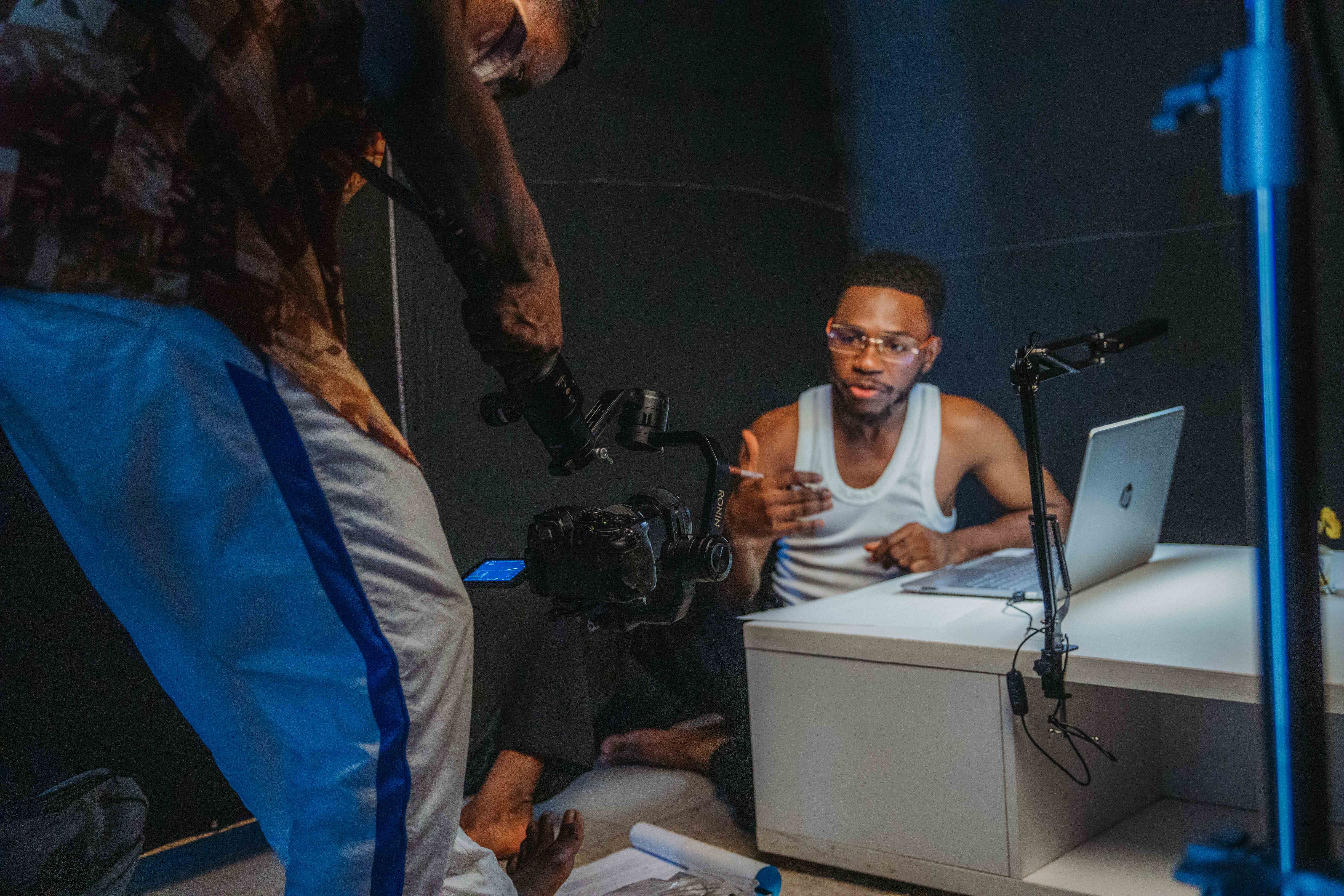 Creators filming together in a home studio with a camera and laptop, illustrating video promotion and audience-building platforms.