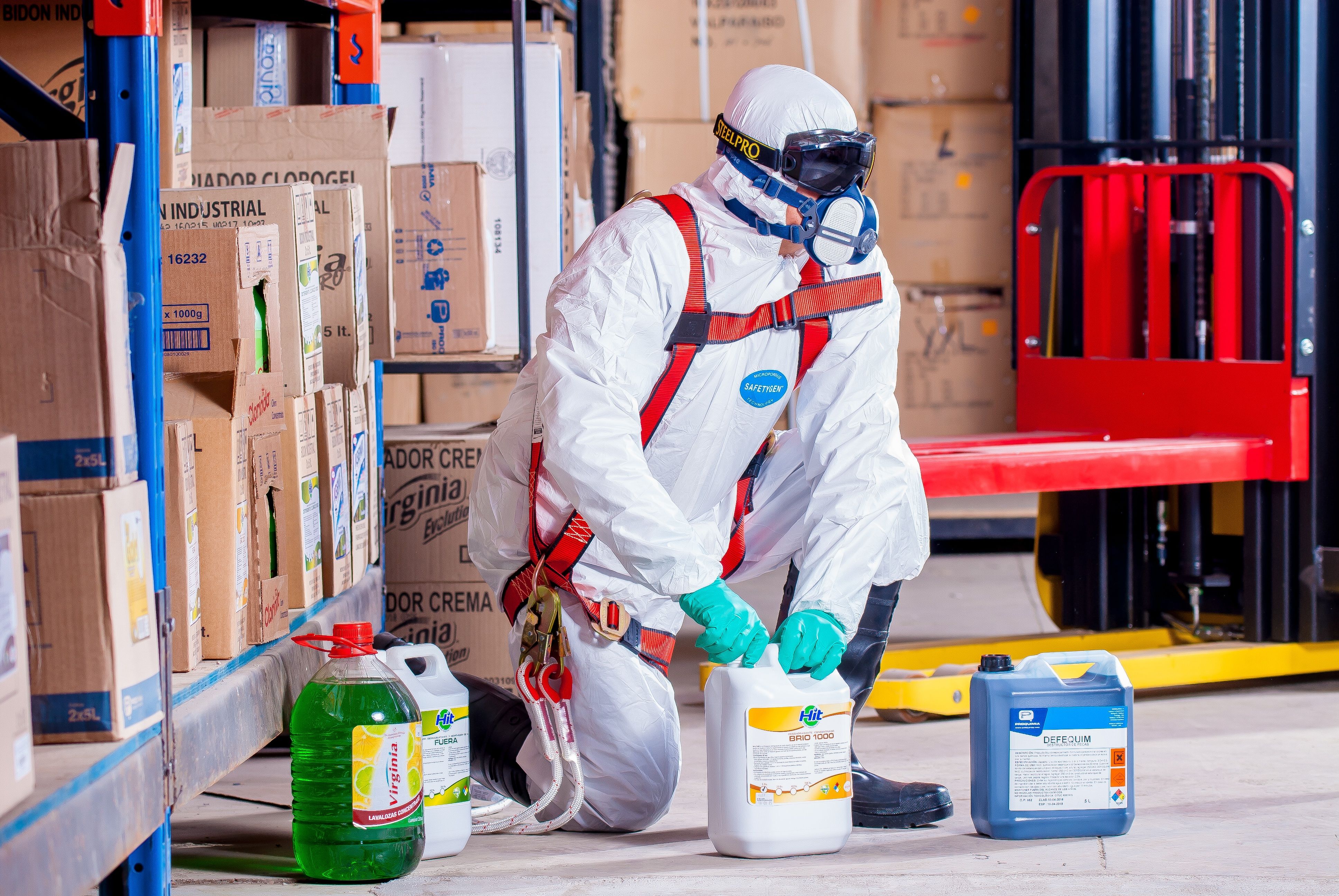 Industrial worker in protective gear handling chemicals in a warehouse
