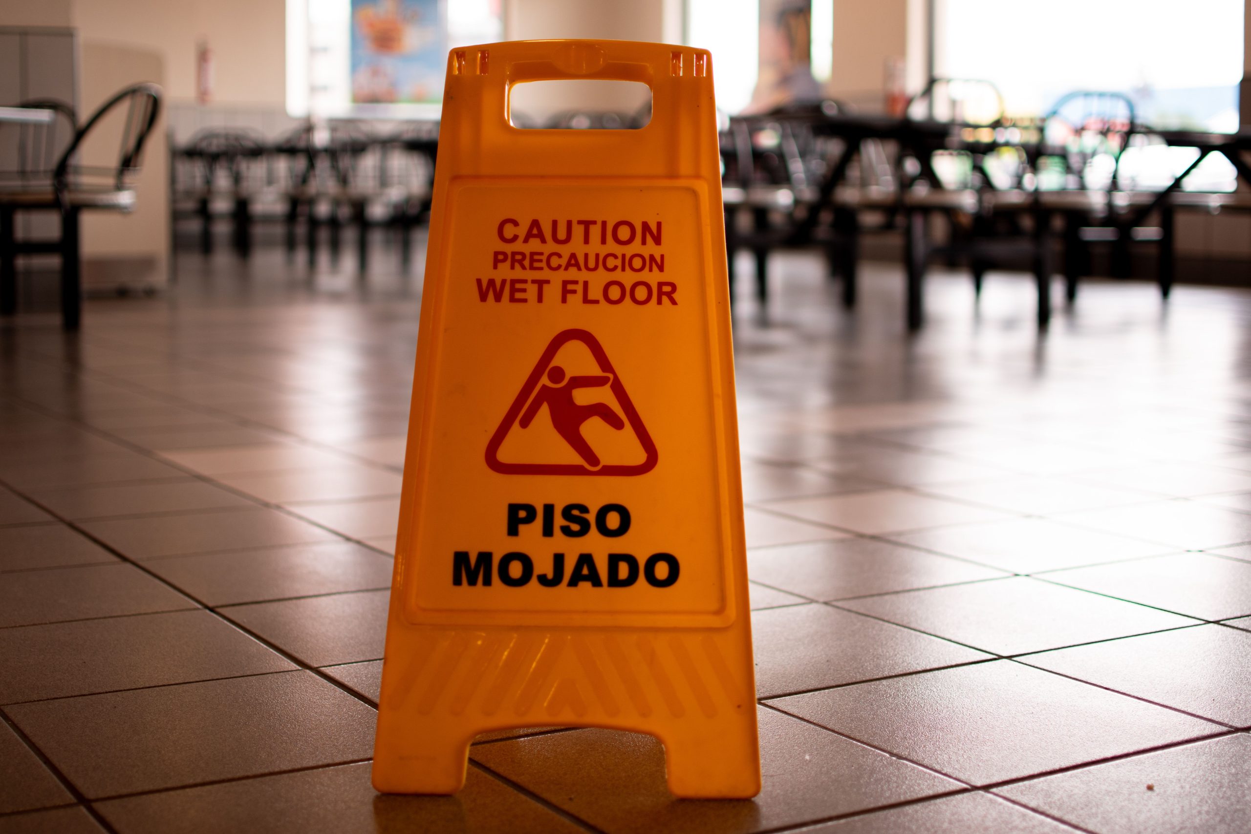 Yellow caution wet floor sign in a cafeteria warning of slippery tiled floor