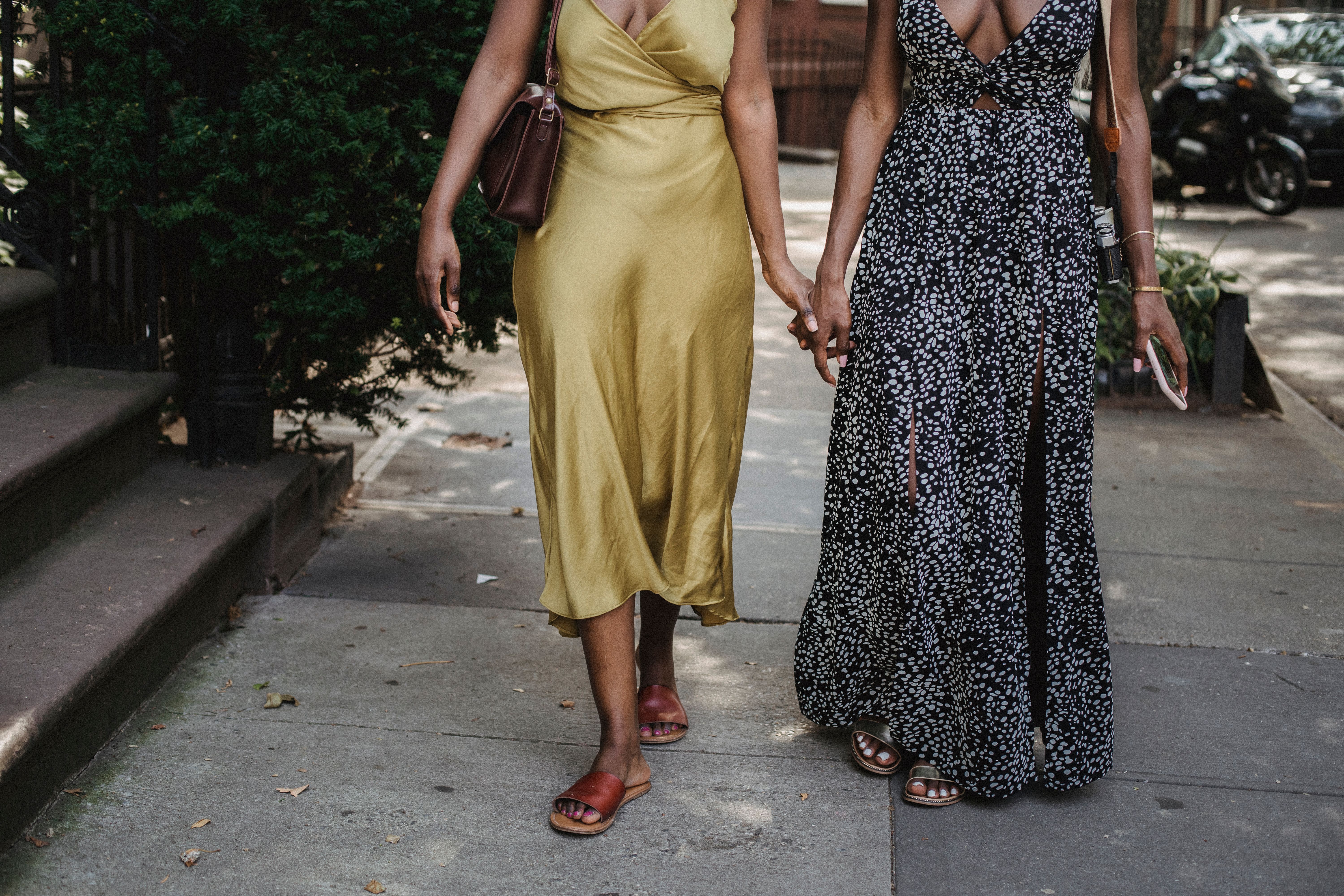Two fashionable women in maxi dresses walking together on an urban sidewalk