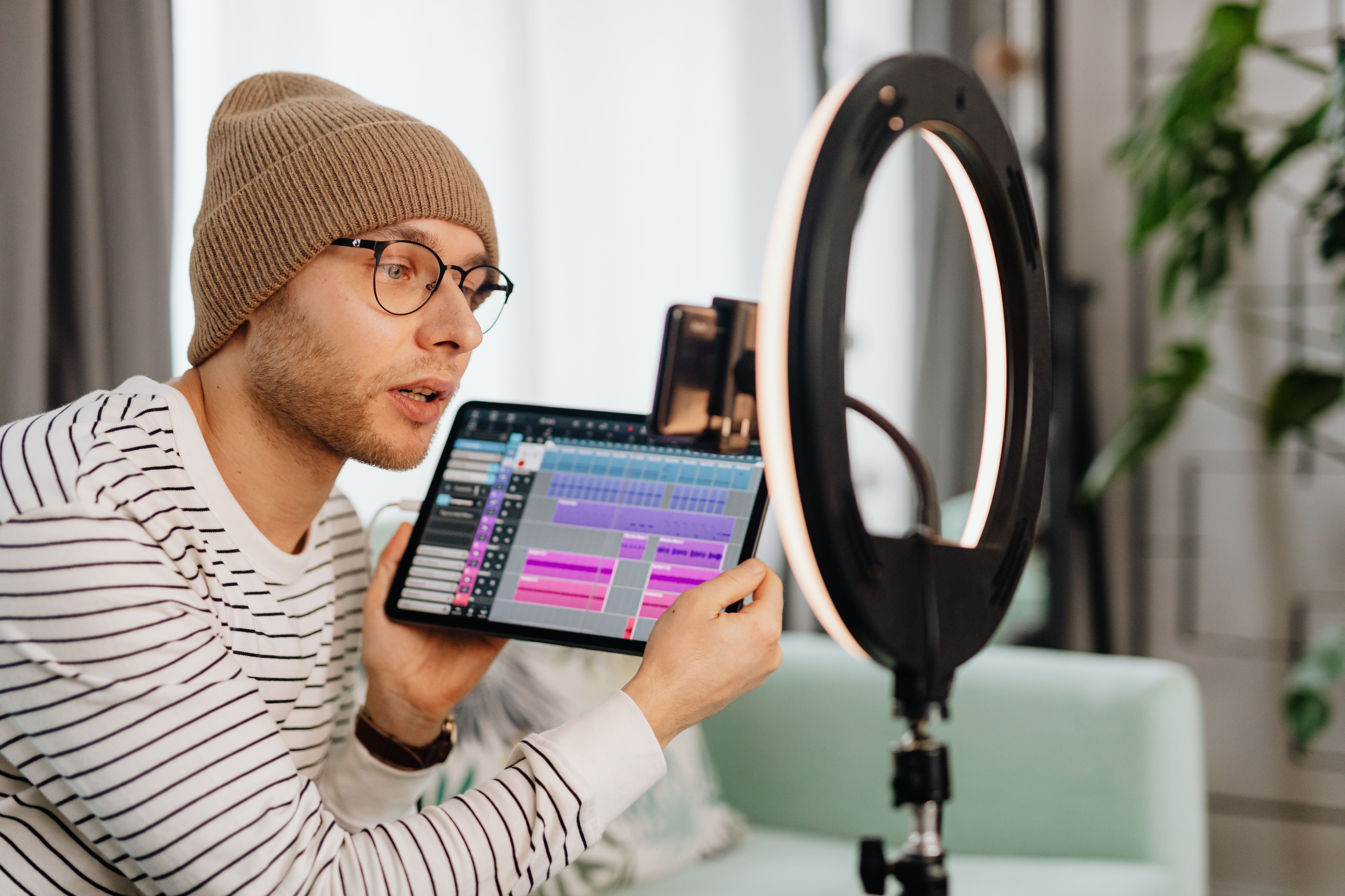 Video creator recording indoors with a tablet and ring light, representing the work behind growing a private YouTube channel.